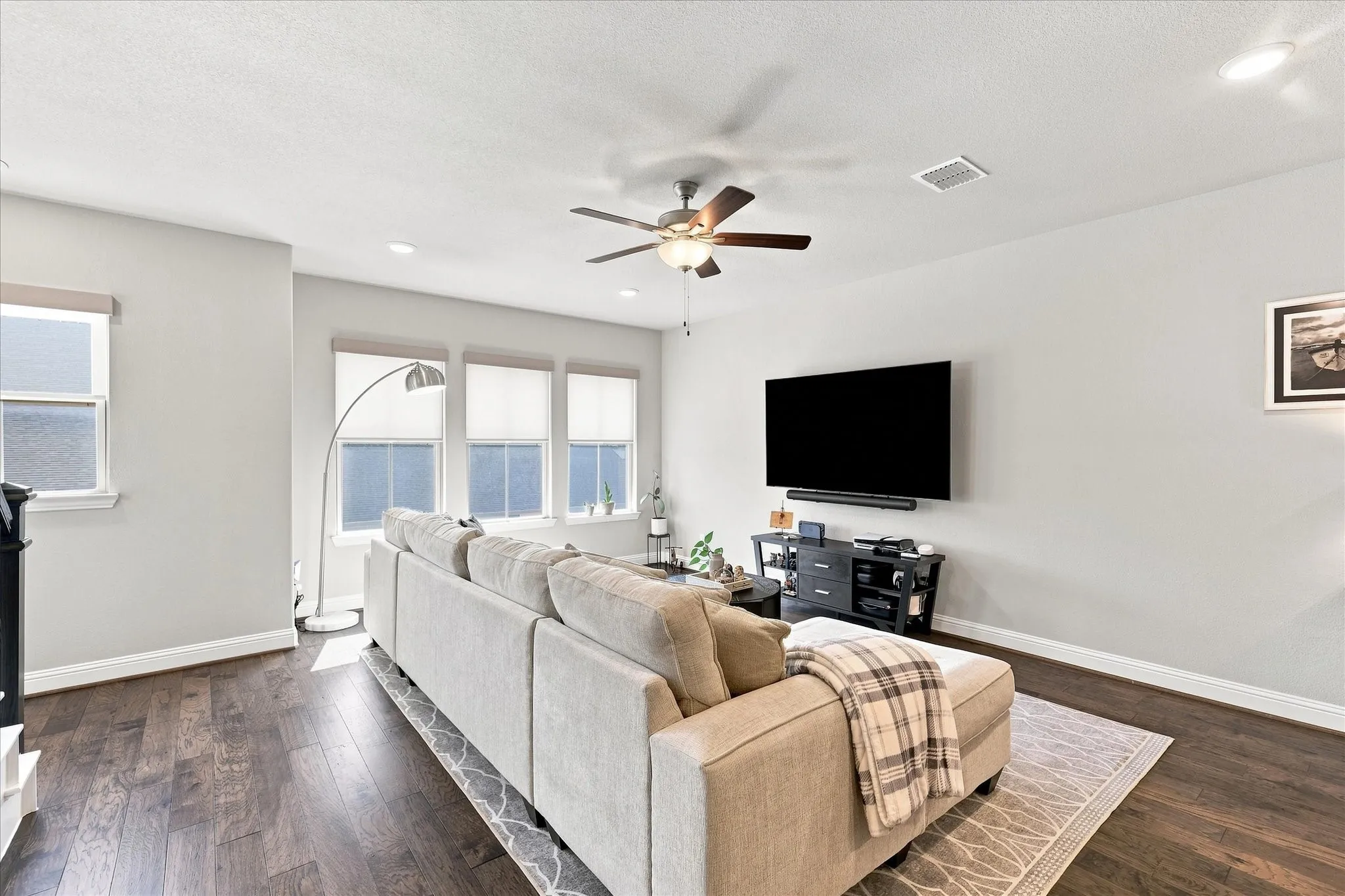 Spacious living area featuring wood-finish flooring, recessed lighting, and multiple windows