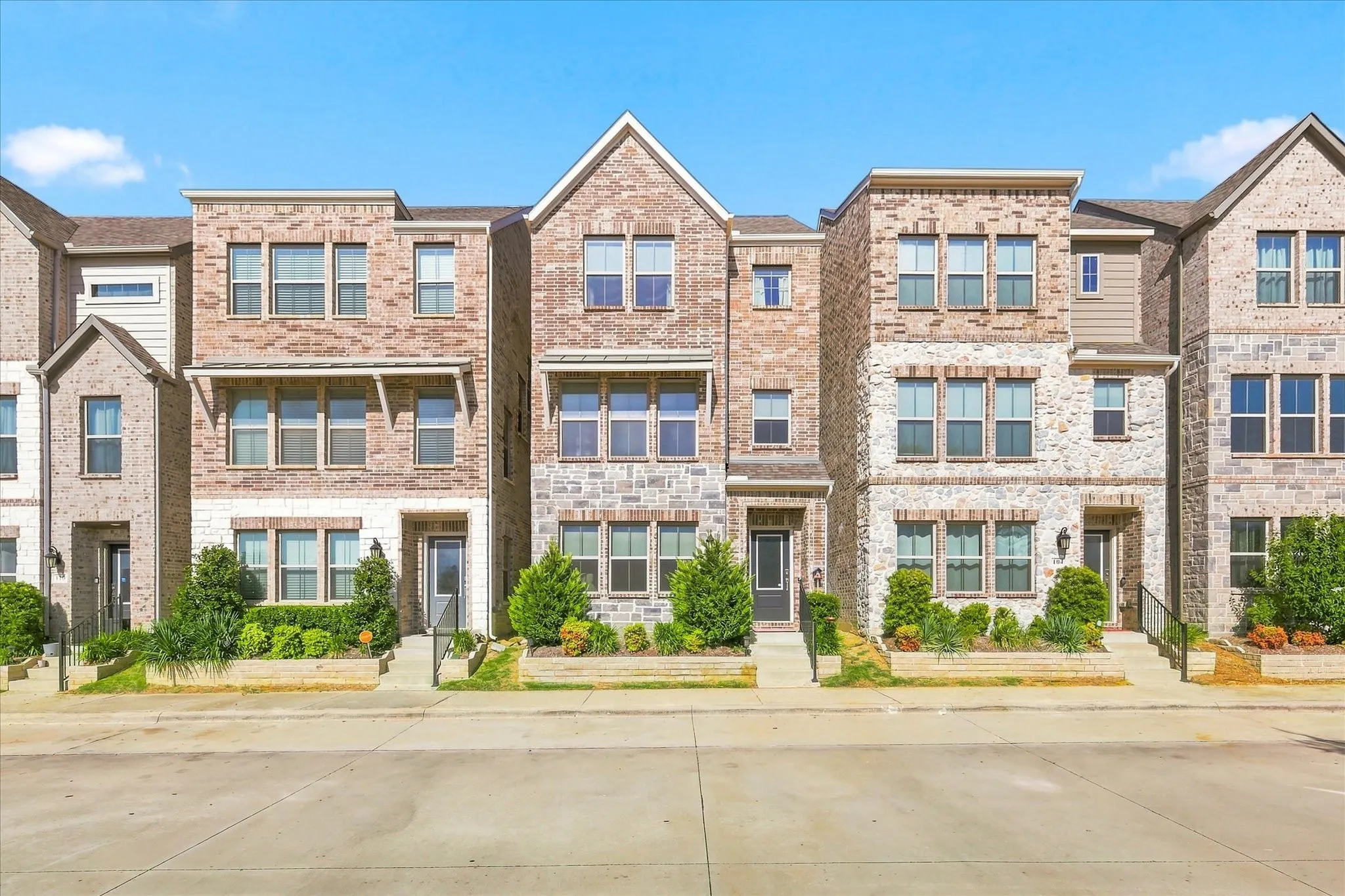 Three-story home with a brick and stone facade, multiple windows, and a prominent peaked roofline