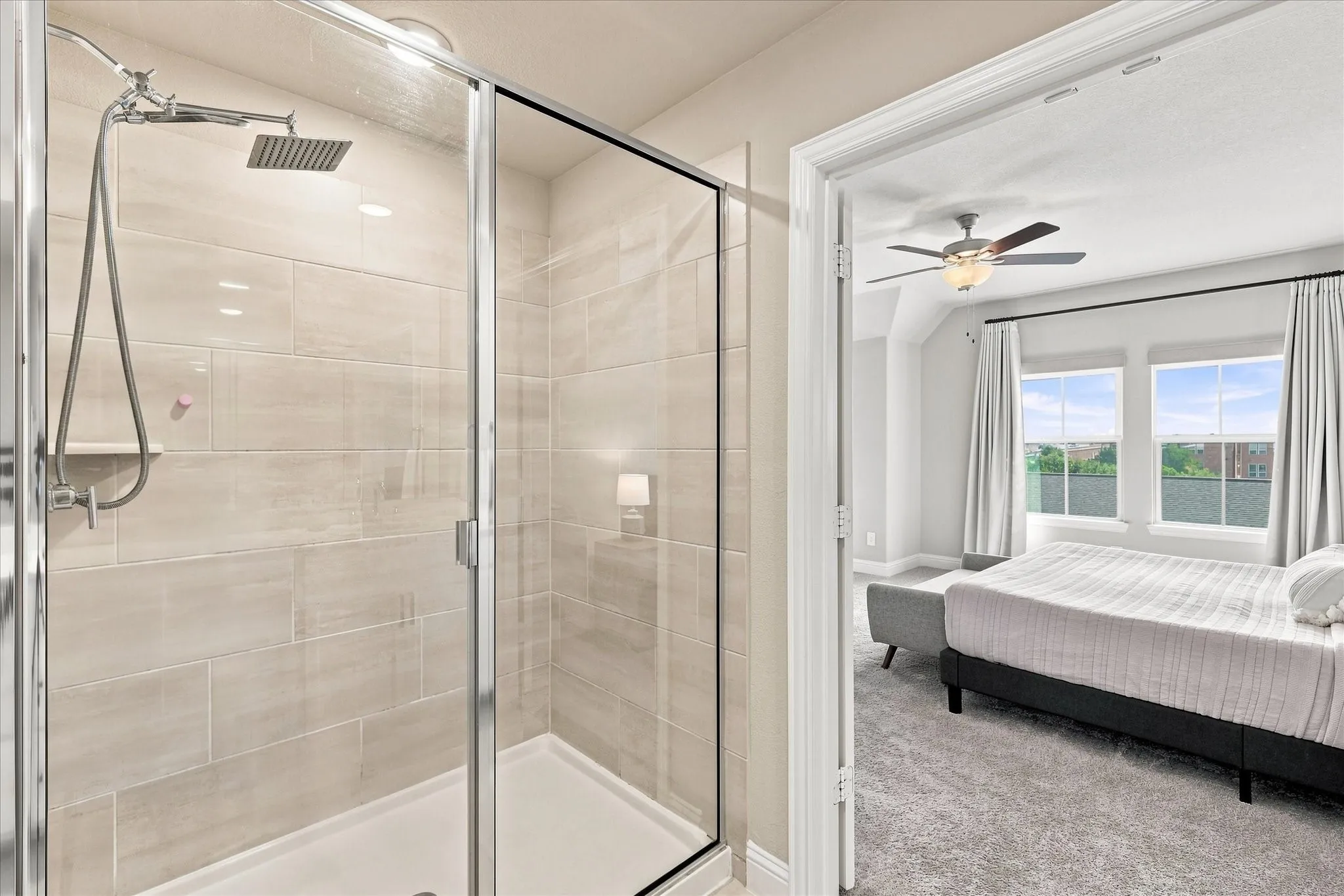Glass-enclosed shower with a rain showerhead, light-toned tile surround, and a built-in shelf