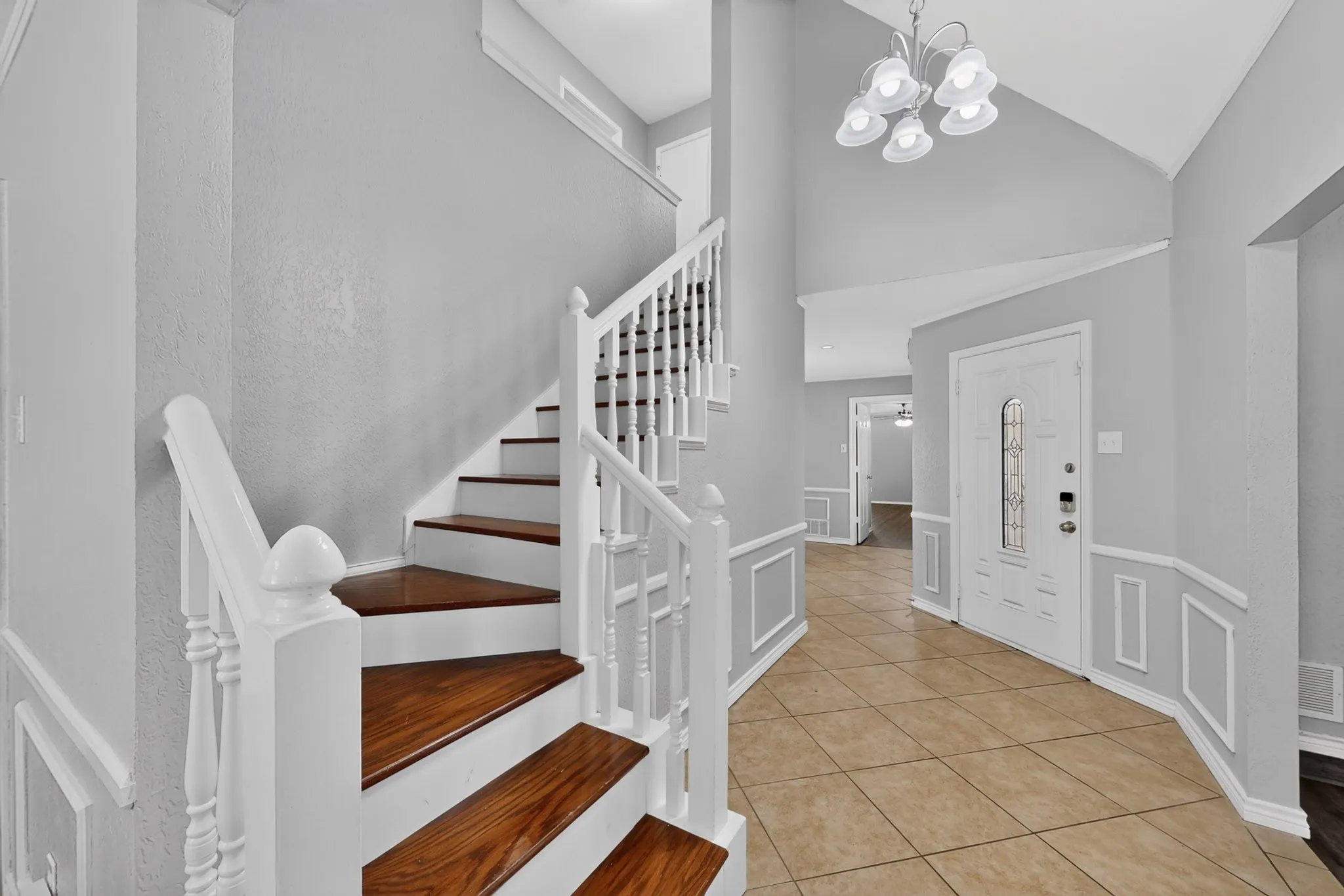Two-story foyer featuring a staircase with wood-finish treads and white risers, white balusters, and a white newel post