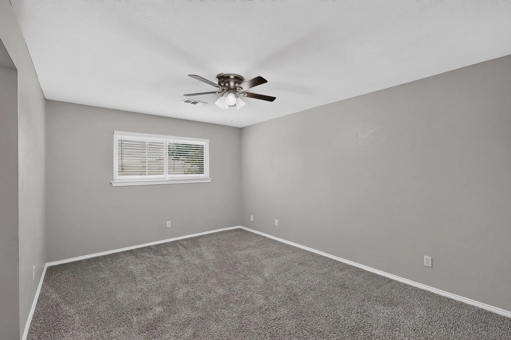 Wall-to-wall carpeting, neutral wall finishes, window with horizontal blinds, and a ceiling fan with integrated lighting
