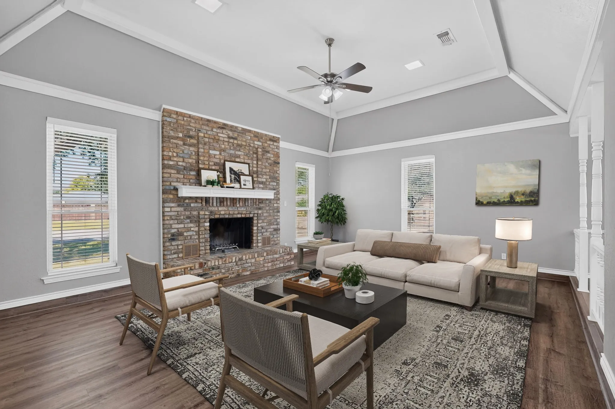 Spacious living area featuring a brick fireplace, wood-finish flooring, and a tray ceiling with a fan