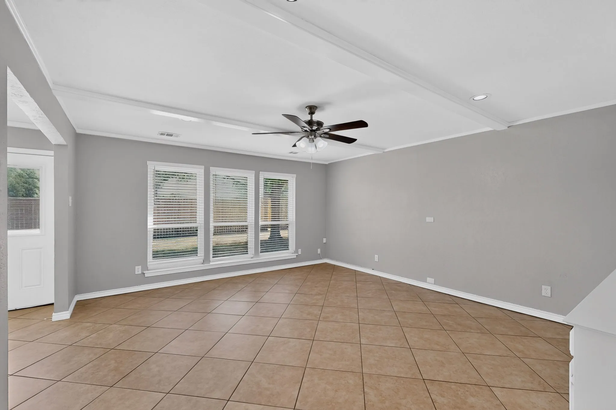 Spacious room featuring neutral grey walls and tile flooring