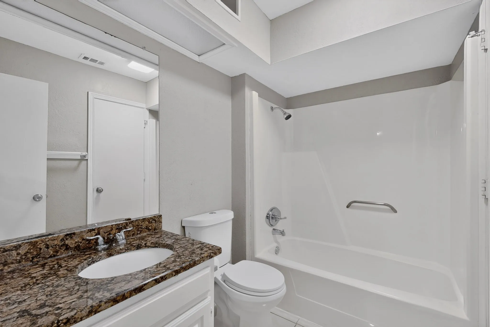 Vanity with a polished stone countertop and integrated sink, chrome faucet, white cabinetry, and a full-width mirror