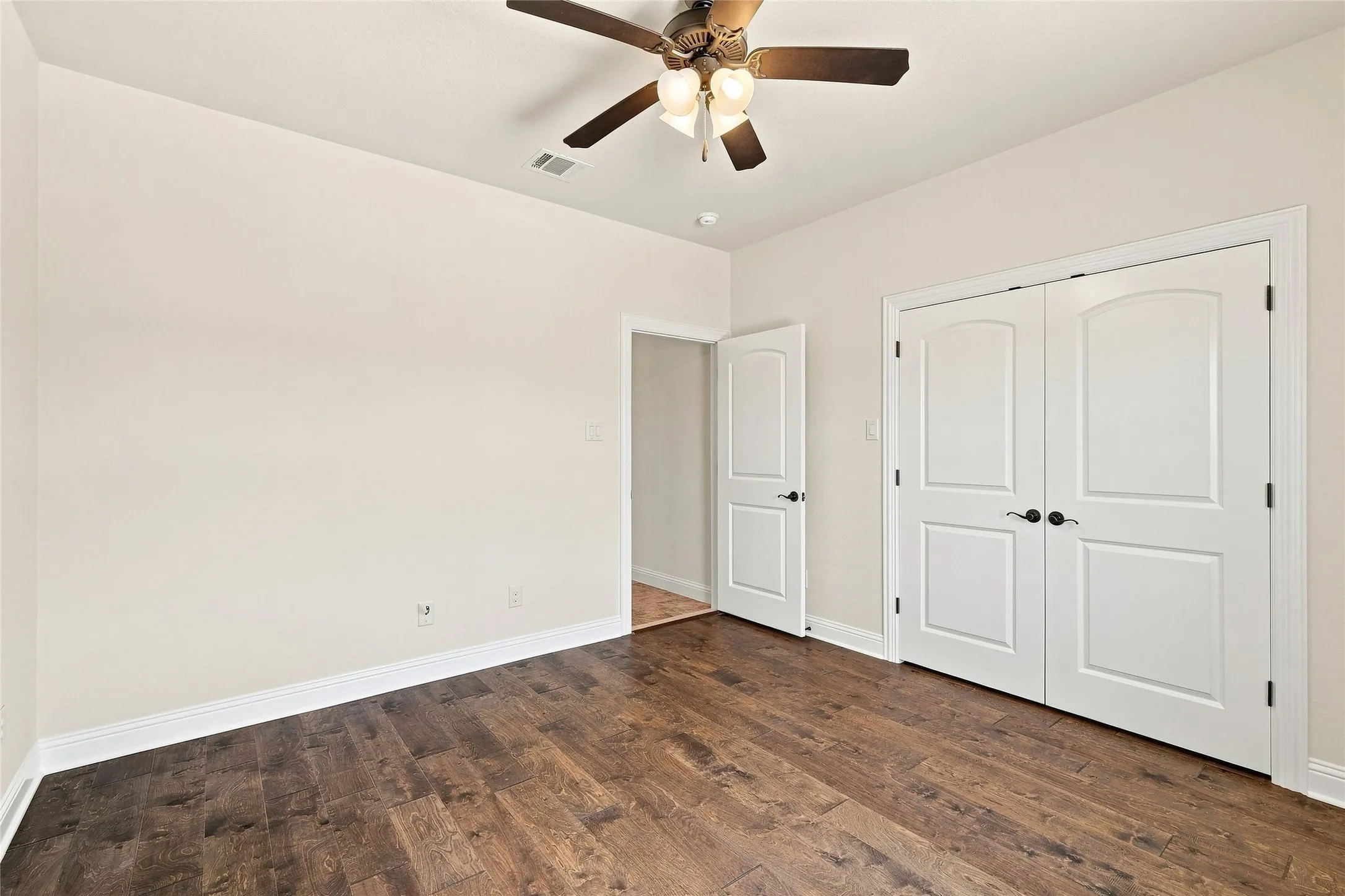 Wood-finish flooring, white walls, and a ceiling fan with light fixture
