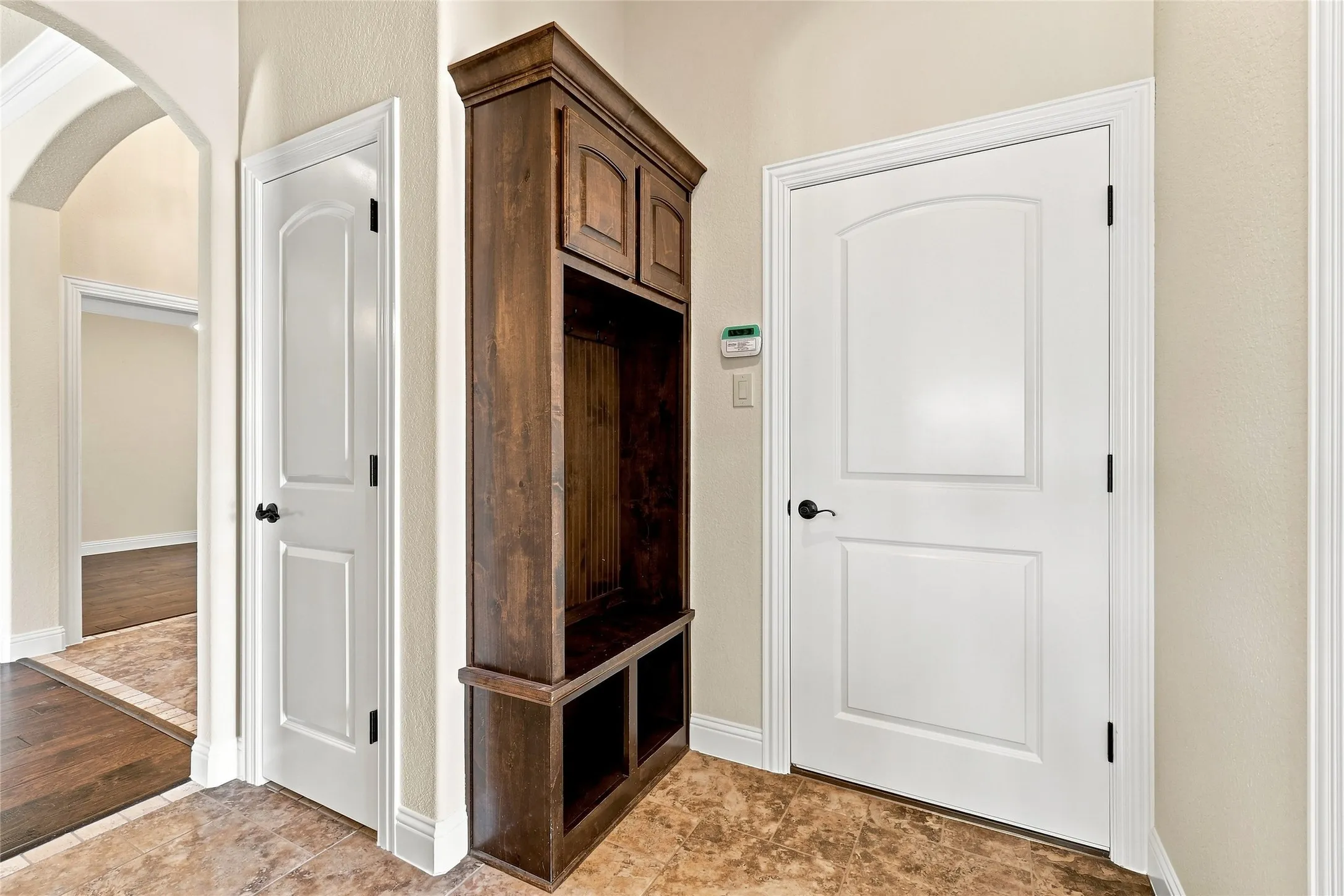 Built-in wood-finish cabinetry, arched doorway, panel doors, and tile flooring