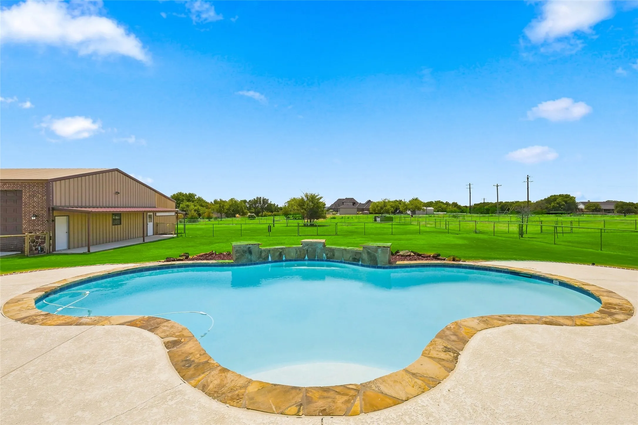 Freeform swimming pool with natural stone coping and integrated water features