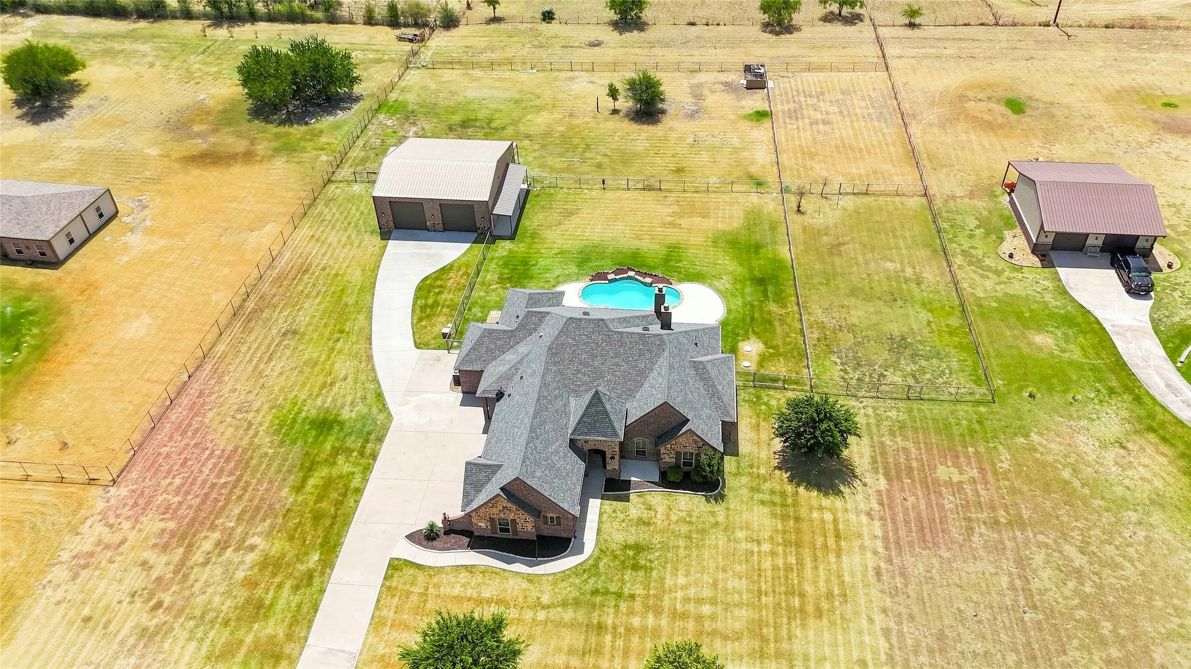 Expansive property featuring a large residence, detached garage structure, and an in-ground swimming pool
