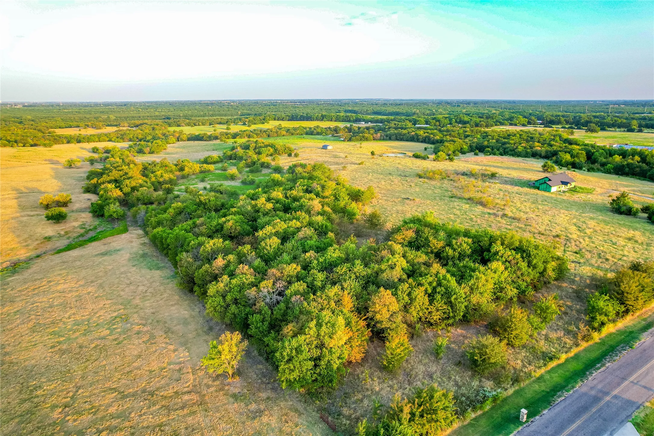 Expansive land parcel featuring open fields and mature tree lines