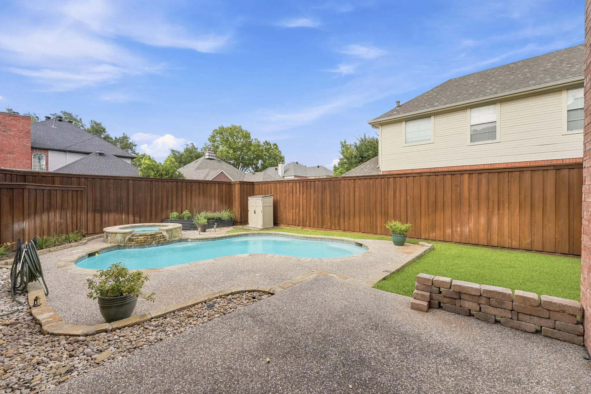 Expansive backyard featuring a swimming pool and an integrated spa, a paved patio, and a manicured lawn area