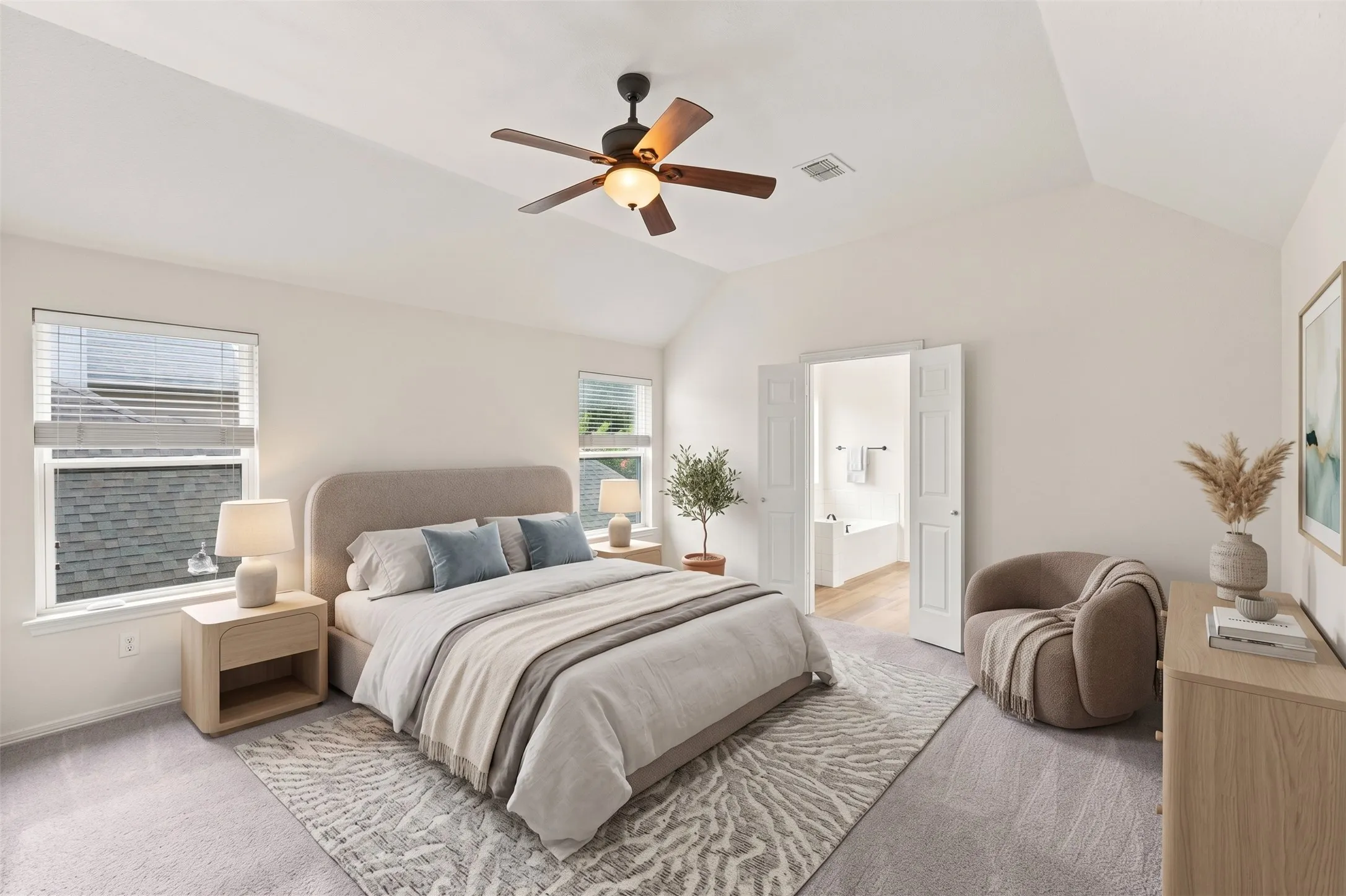 Vaulted ceilings with a ceiling fan, dual windows with blinds, plush carpet flooring, and an en-suite bathroom access