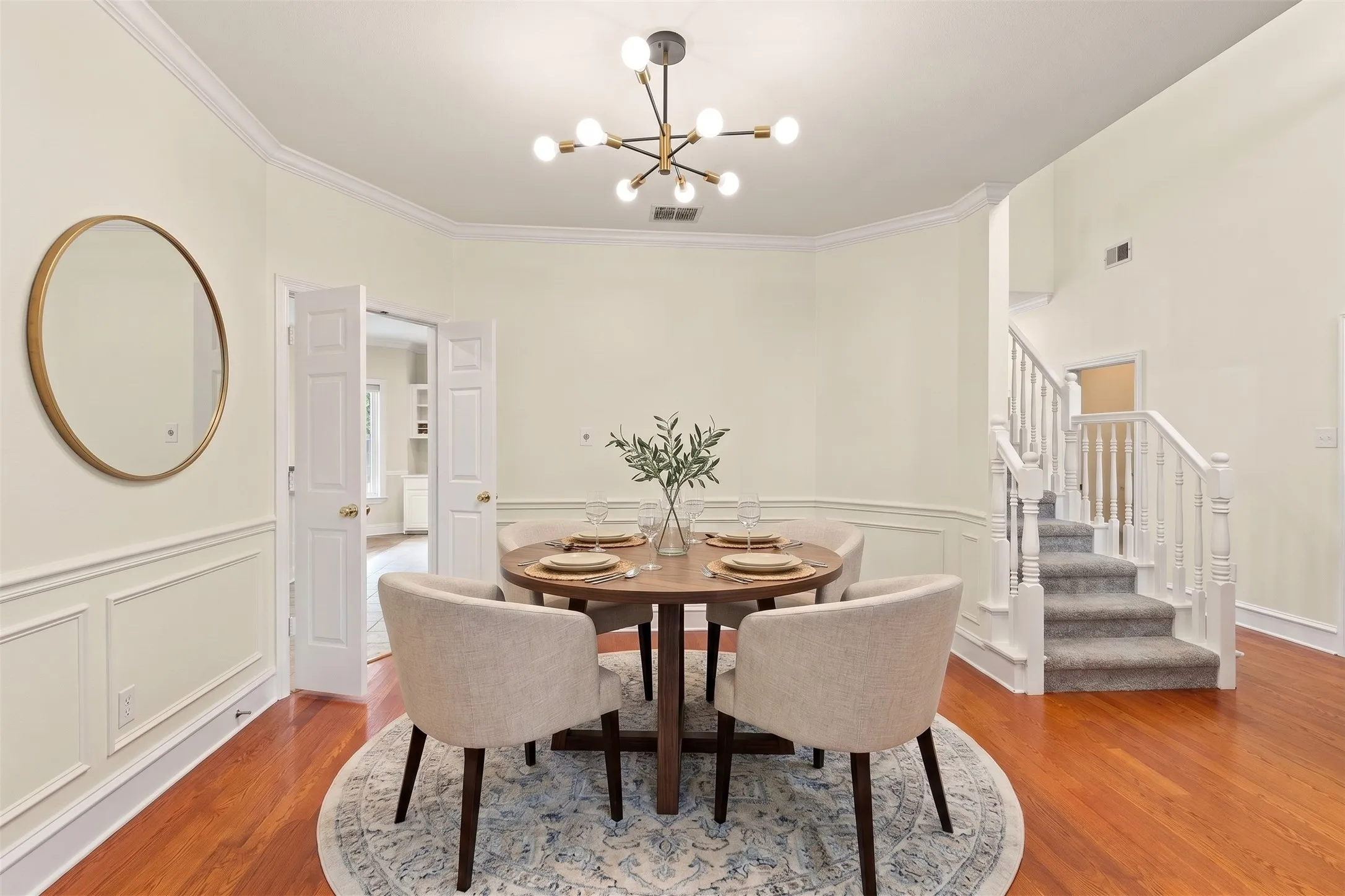 AI generated staging furniture  - Hardwood-finish flooring, wainscoting, crown molding, modern chandelier, and a carpeted staircase with white balusters