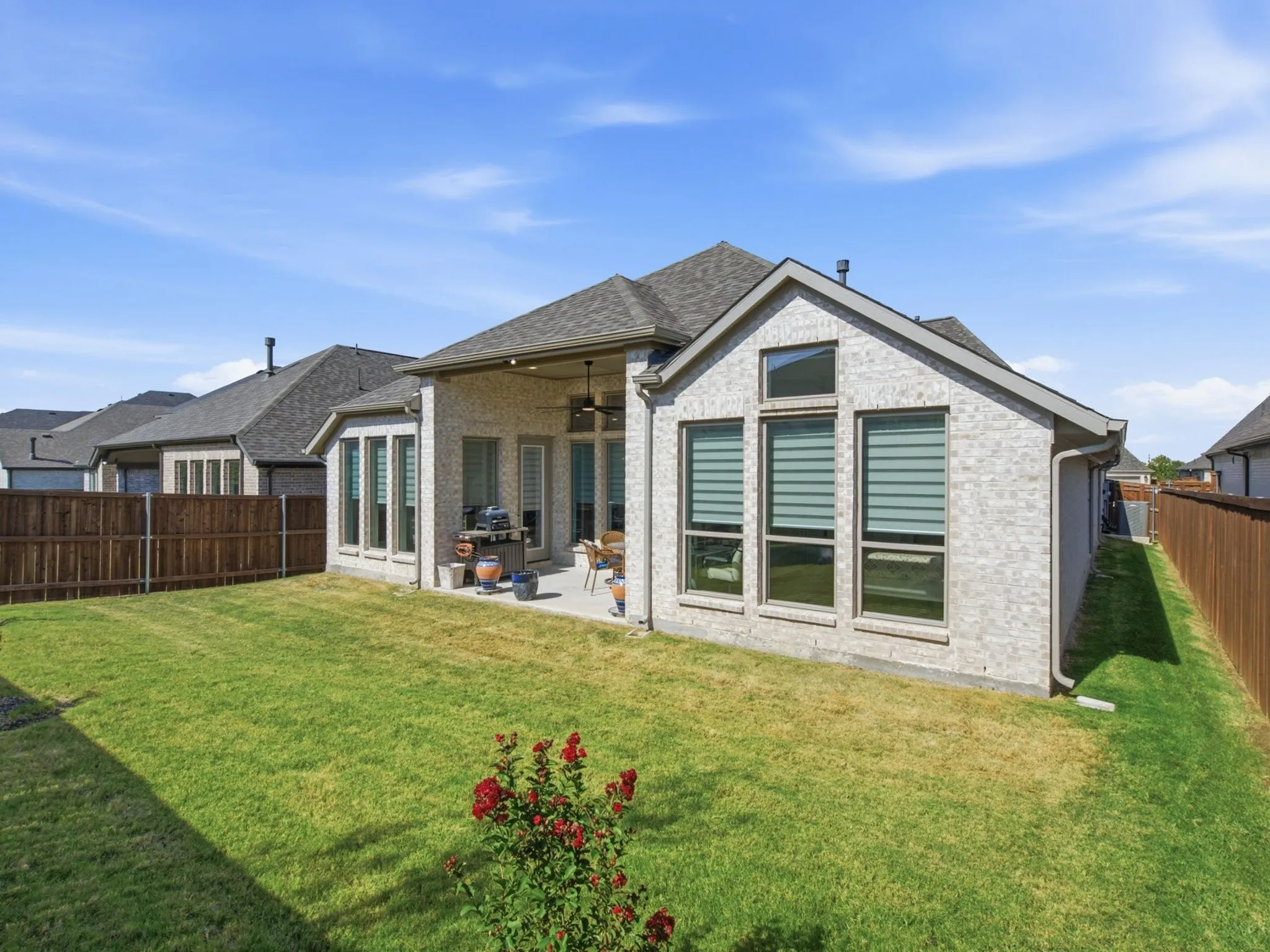 Expansive backyard with a covered patio, manicured lawn, and privacy fencing