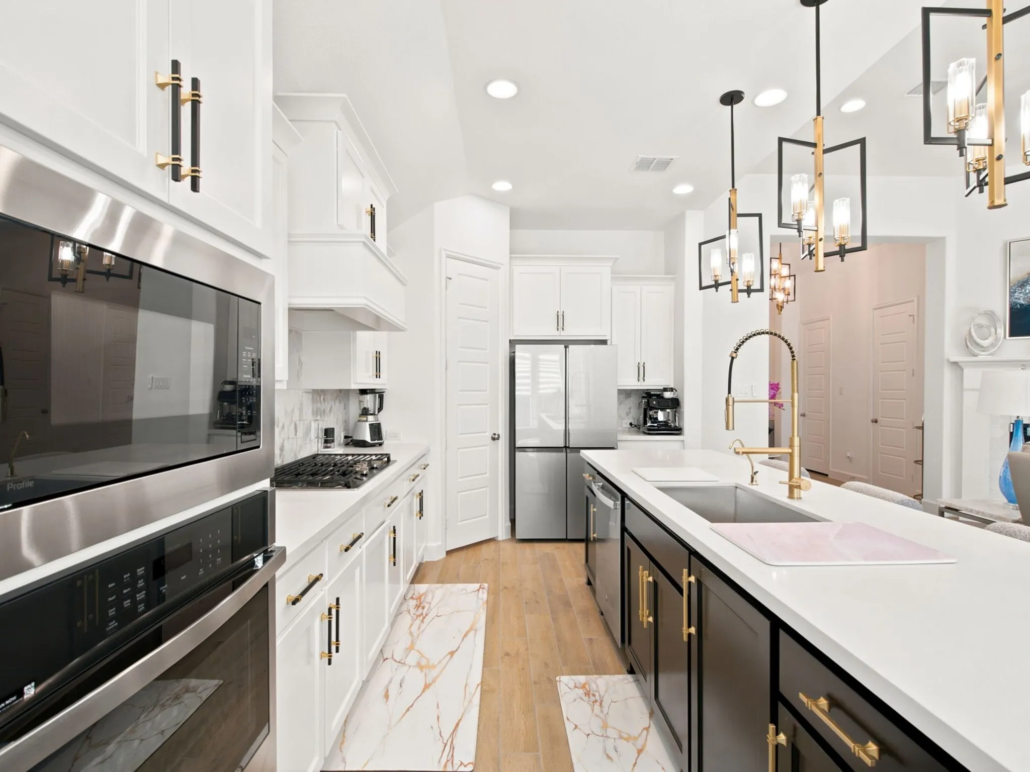 Modern kitchen featuring stainless steel appliances, white cabinetry, a kitchen island with seating, a gas cooktop, and brass-finish hardware
