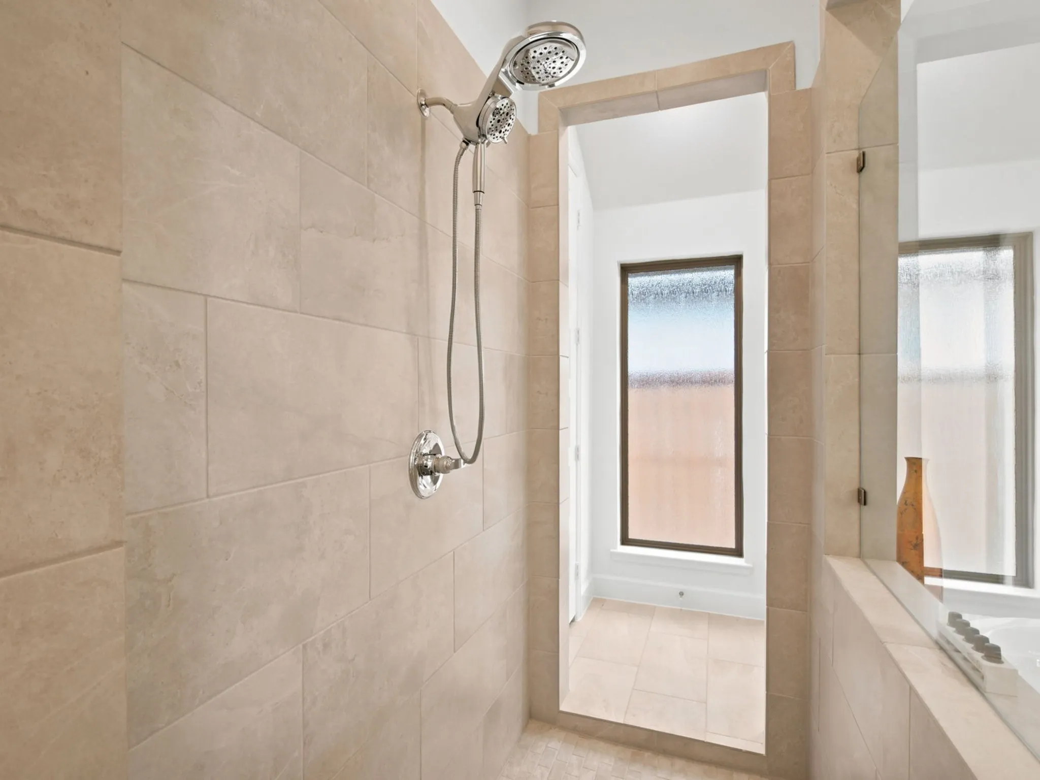Tiled shower enclosure with a chrome-finish shower head and control