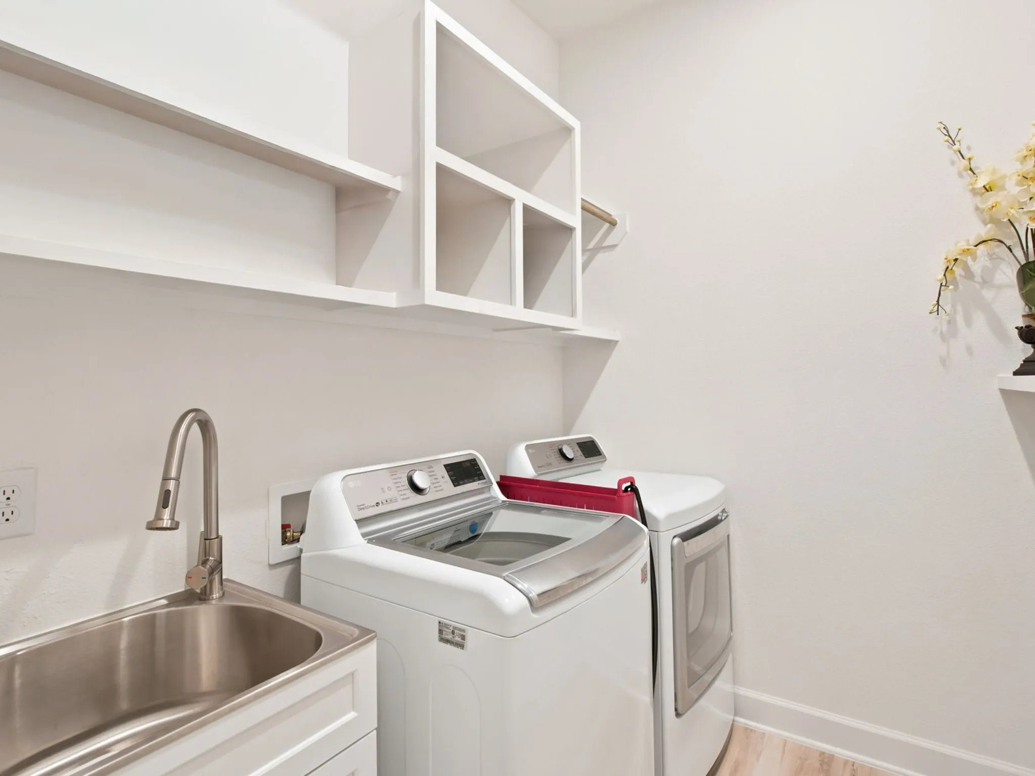 Laundry room with a stainless steel utility sink, a gooseneck faucet, white shaker cabinetry, and open shelving