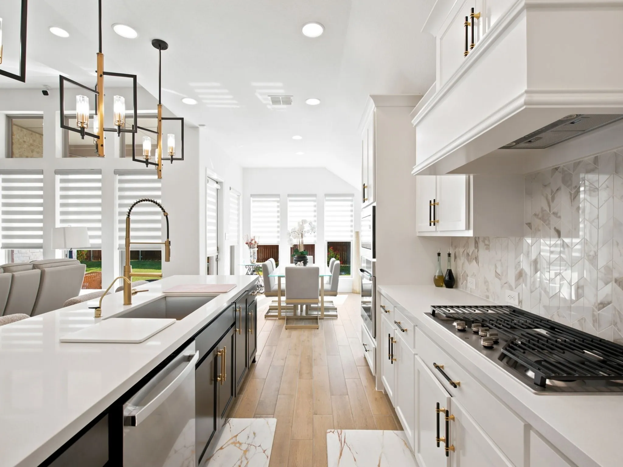White cabinetry with gold-finish hardware, built-in gas cooktop, patterned tile backsplash, wood-finish flooring, and recessed lighting