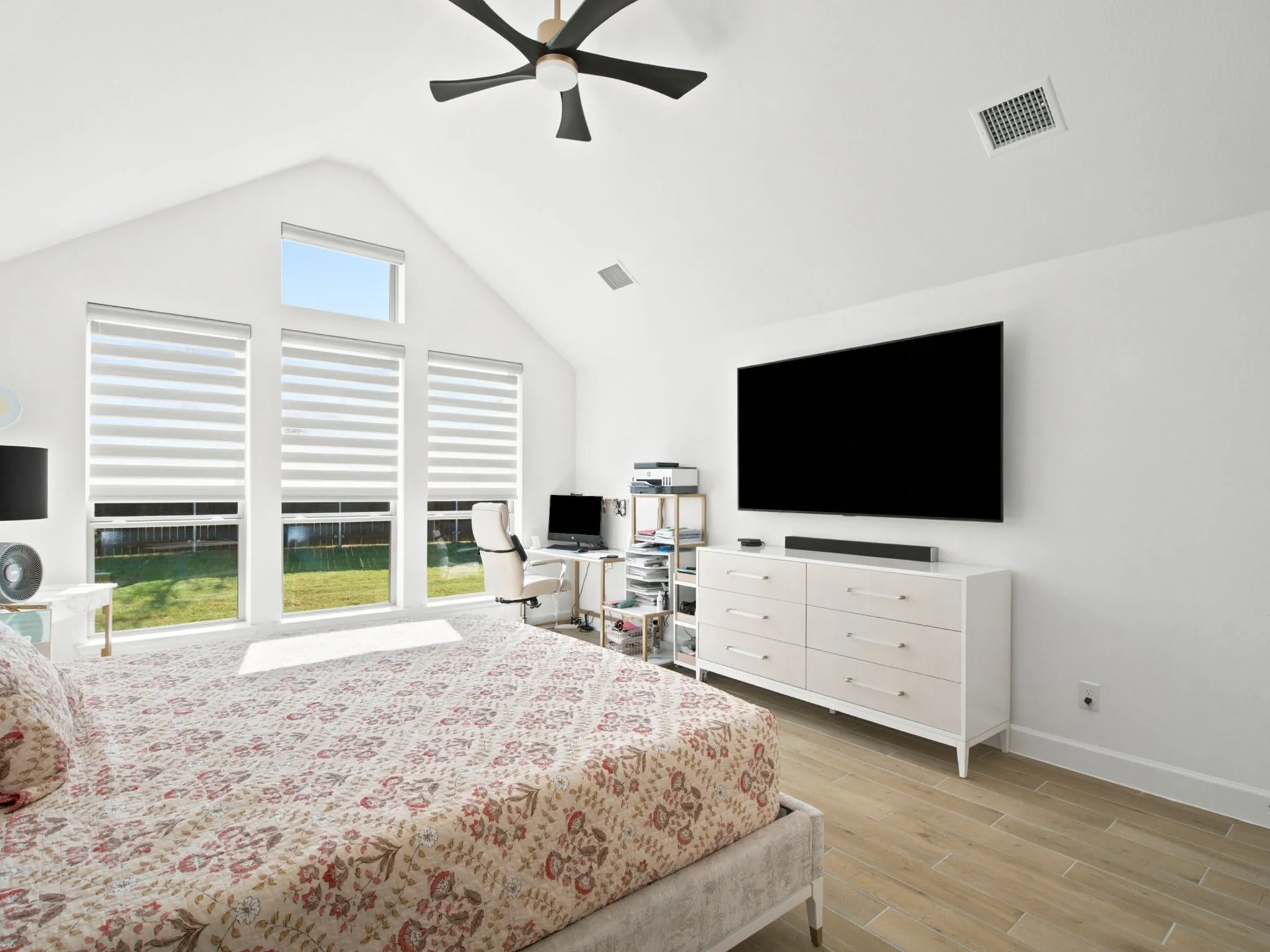 Vaulted ceiling, multiple large windows, wood-finish flooring, ceiling fan, built-in dresser