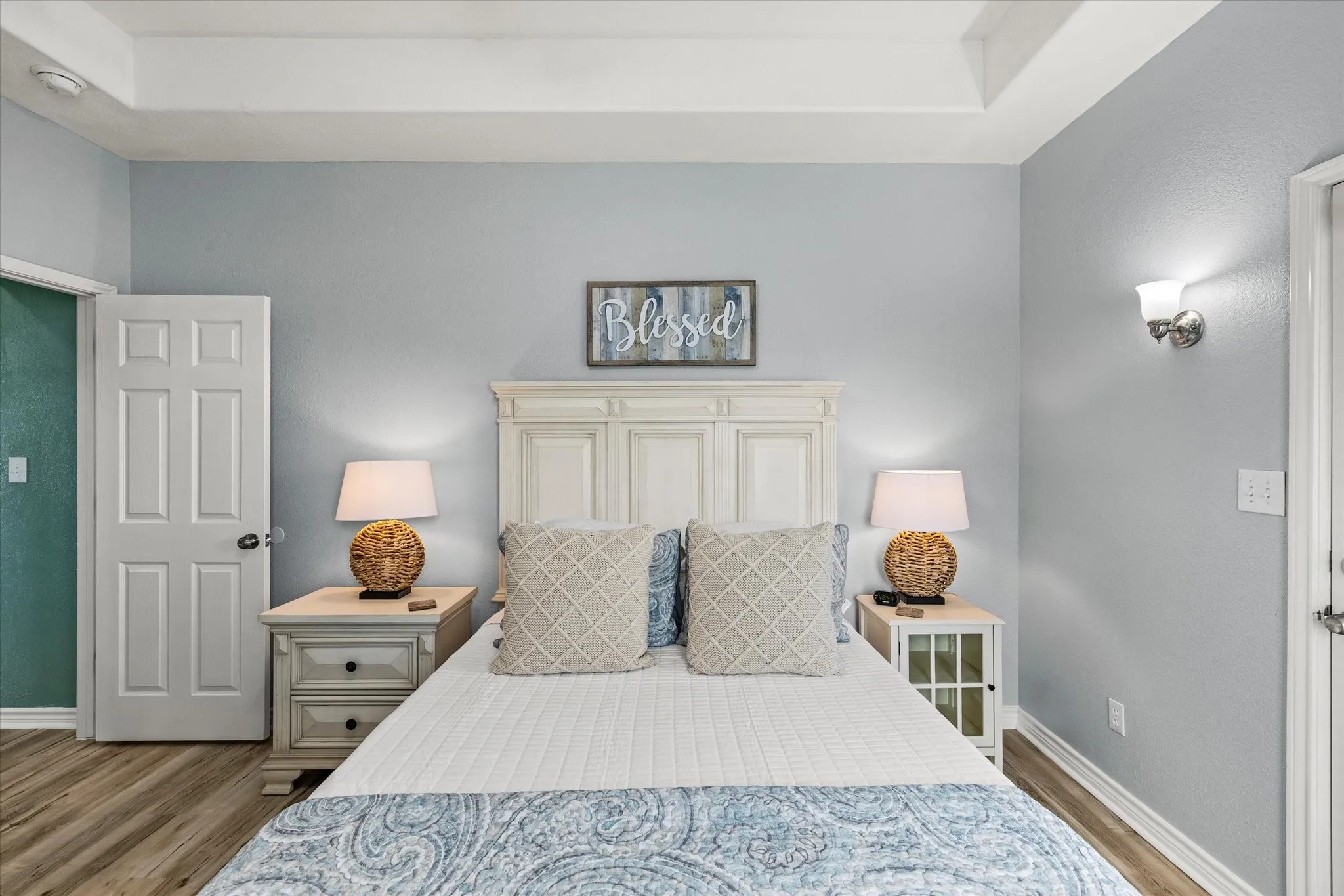 Bedroom 2 with nightstands and lamps. Exterior door to deck on the right. Hall bathroom to the left