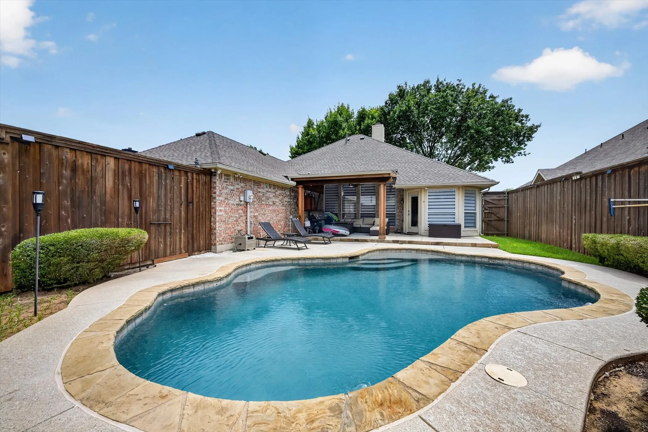 Resort-style pool with a stone coping and a surrounding concrete patio