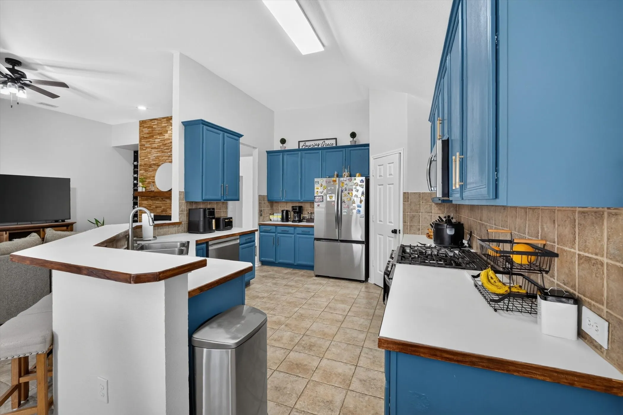 Kitchen featuring blue cabinetry, white countertops, stainless steel appliances, and tile flooring
