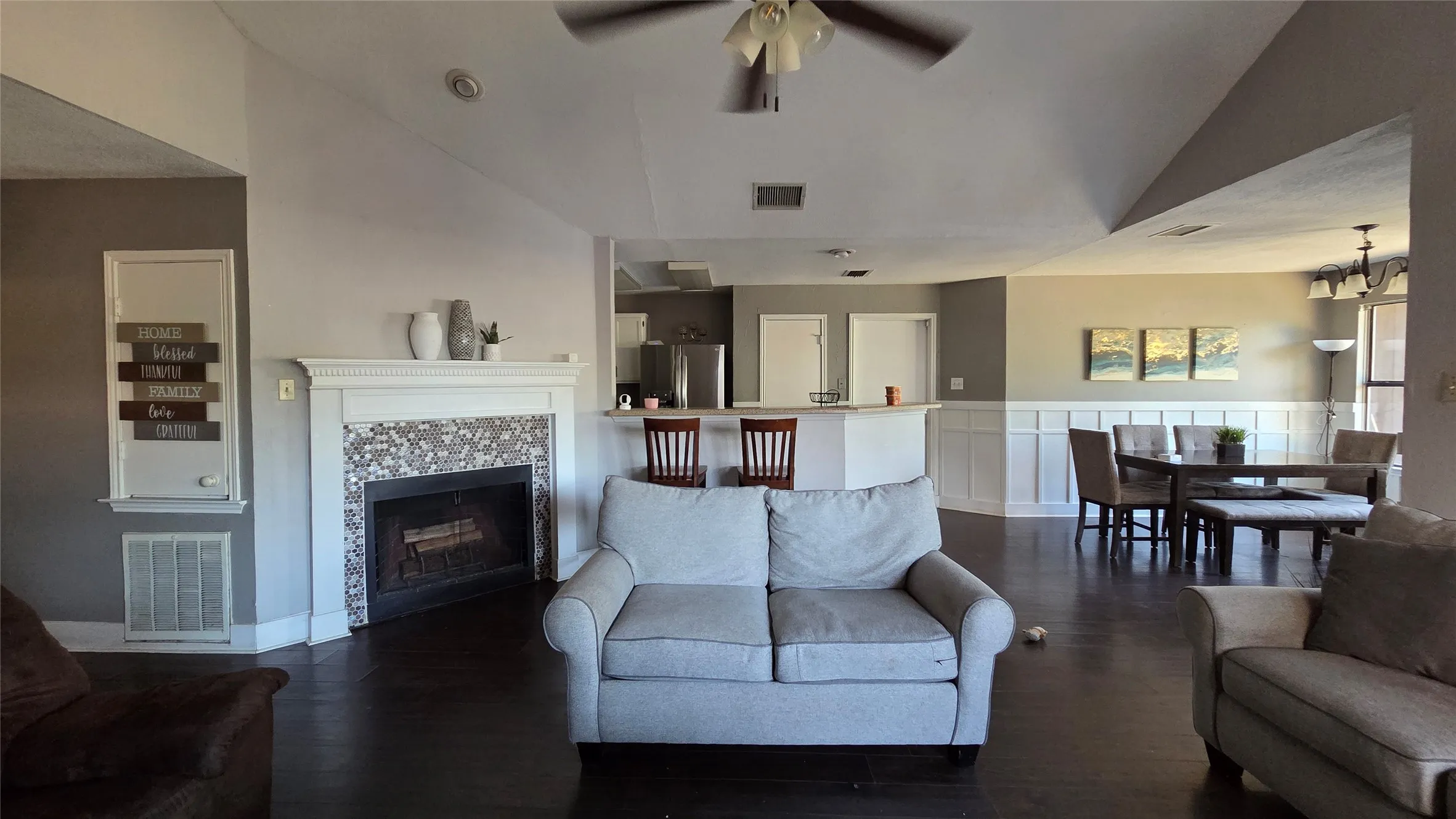 Vaulted ceilings, wood-finish flooring, fireplace with decorative tile surround, built-in breakfast bar, and wainscoting