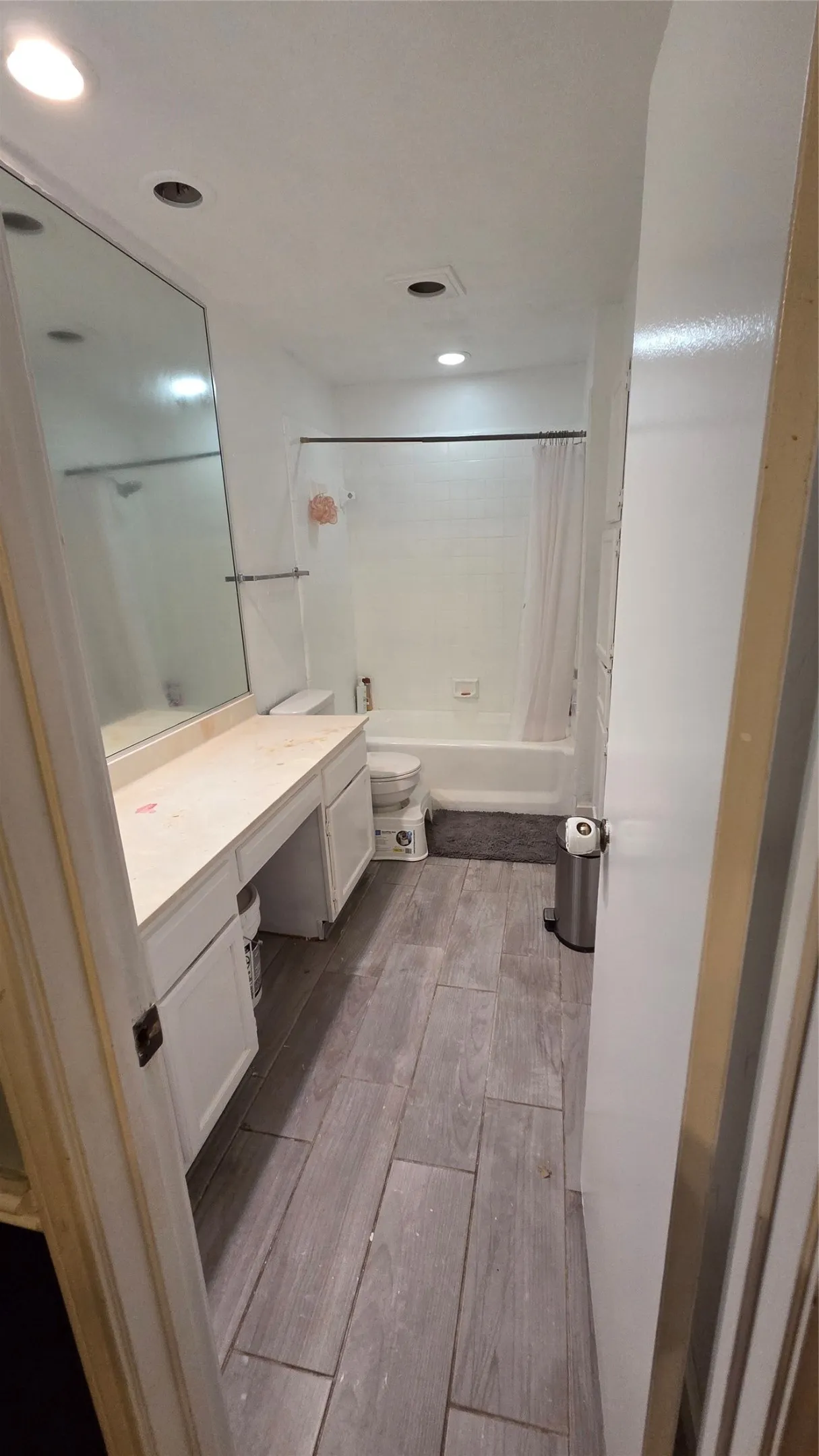 Bathroom featuring wood-finish tile flooring, a built-in vanity with extensive counter space, and a combination bathtub/shower