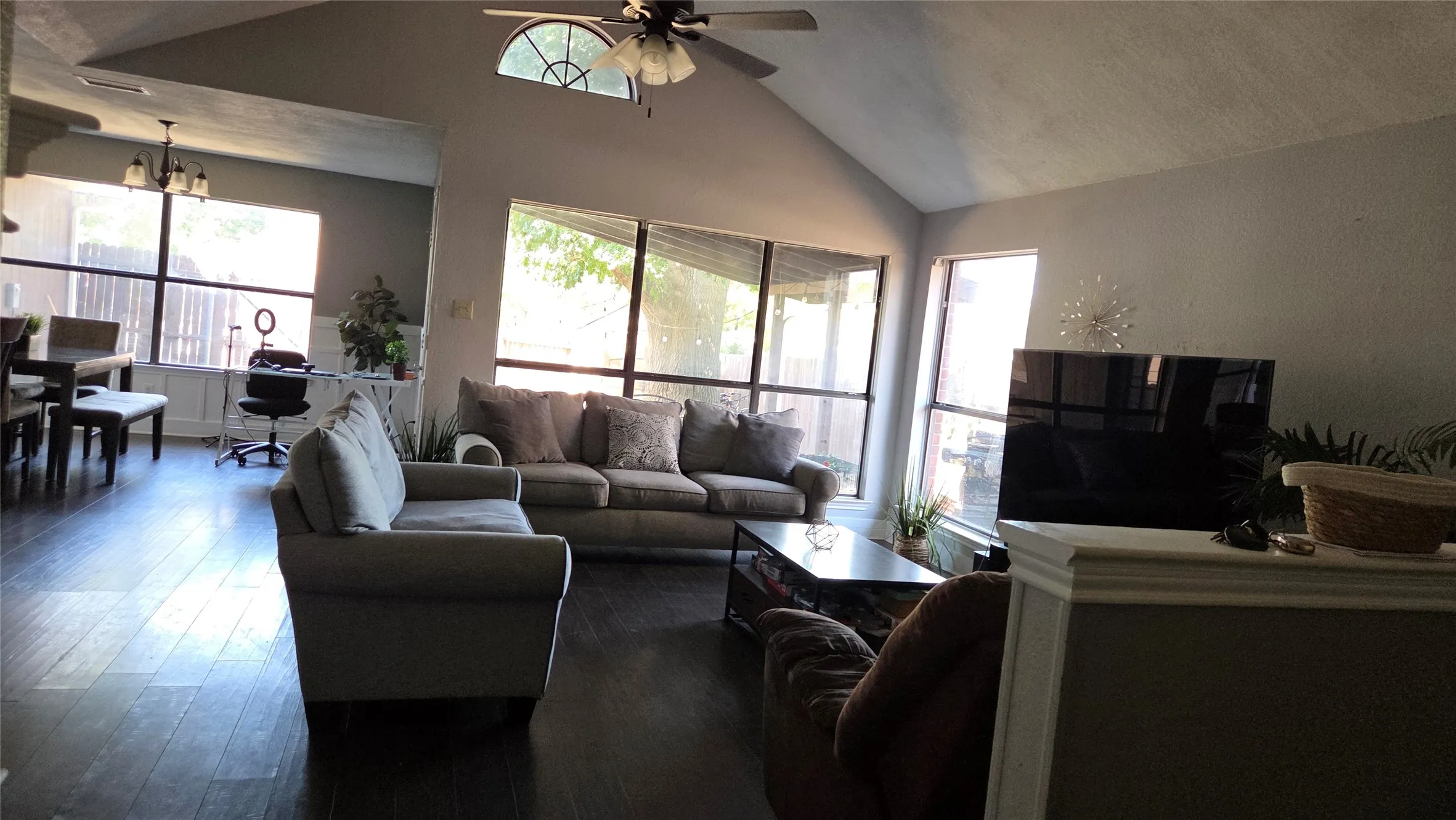 Vaulted ceiling with a ceiling fan, wood-finish flooring, and expansive windows