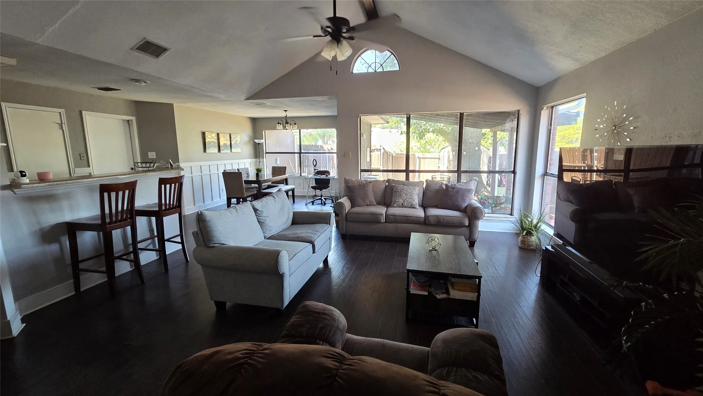 Vaulted ceiling with an arched transom window, dark wood-finish flooring, and a breakfast bar
