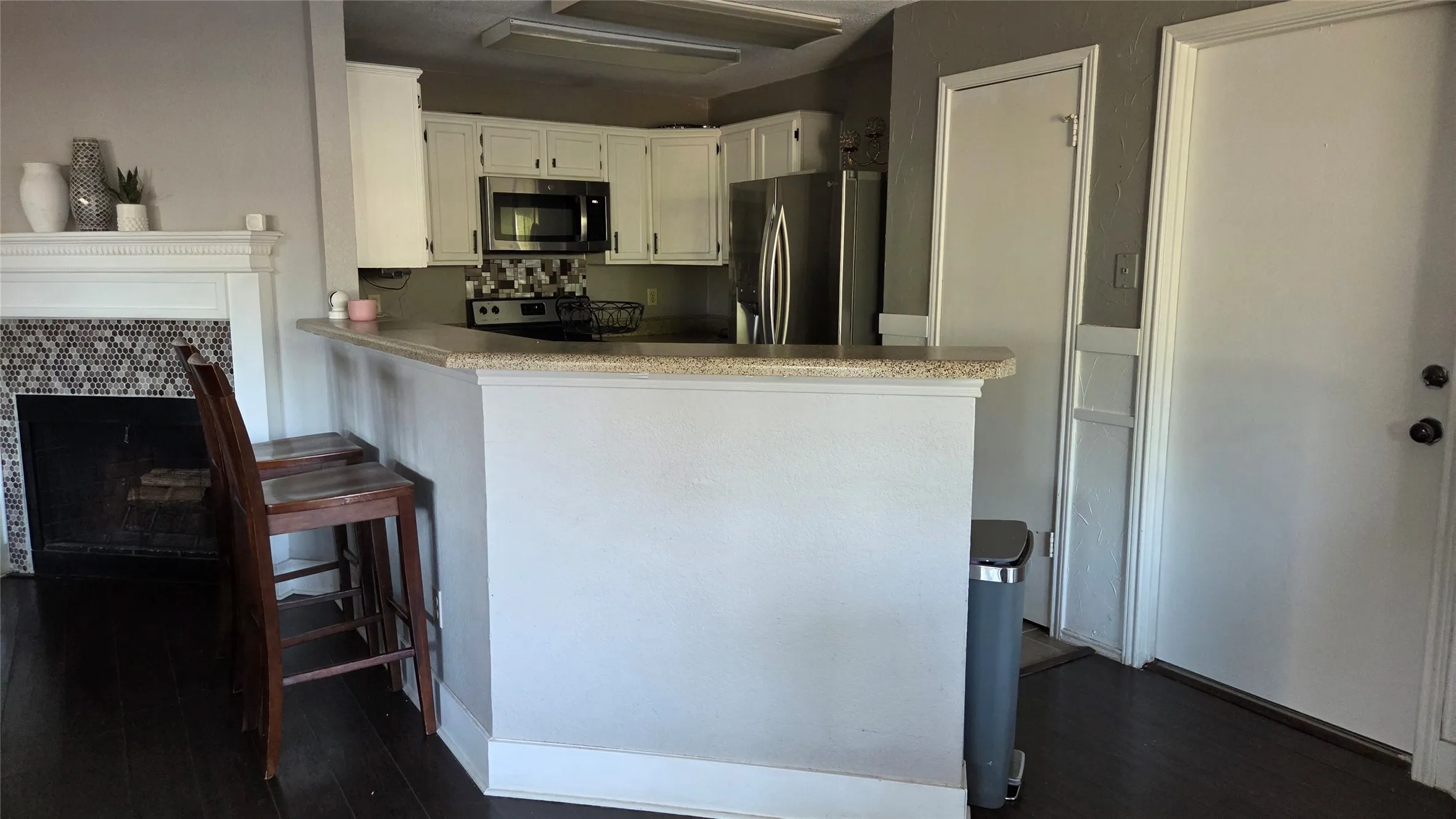 Kitchen with white cabinetry, stainless steel appliances, breakfast bar, and wood-finish flooring