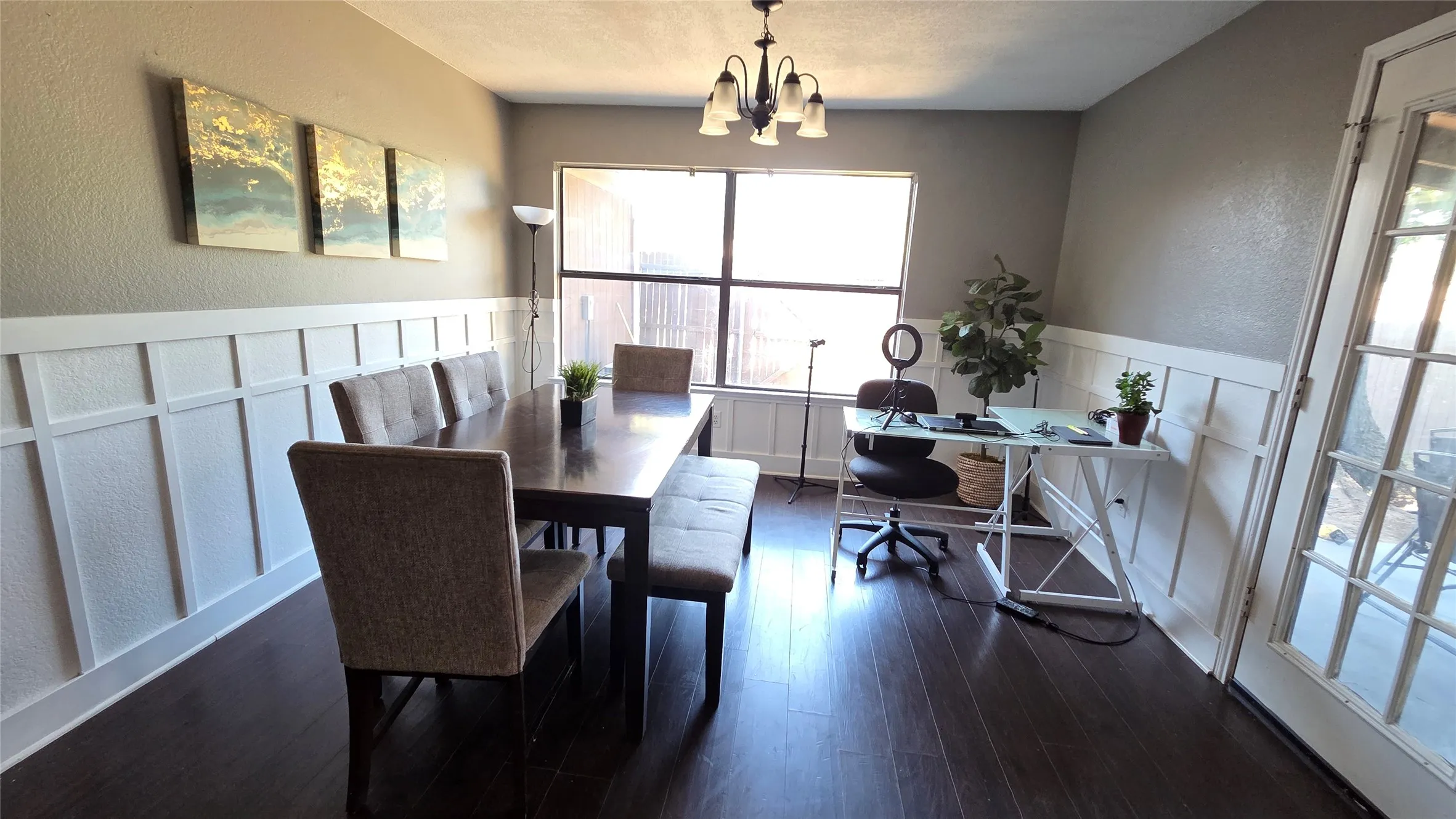 Wood-finish flooring, wainscoting, an overhead chandelier, and a large window
