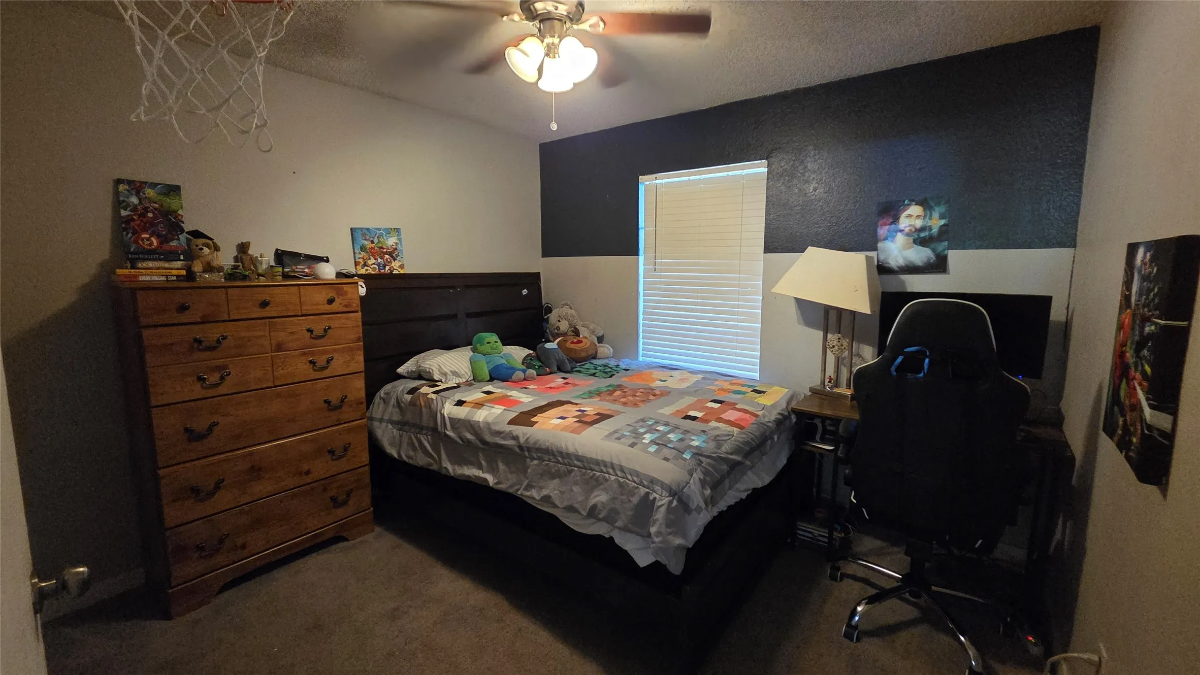 Carpeted bedroom featuring a ceiling fan, window with blinds, and a two-toned wall