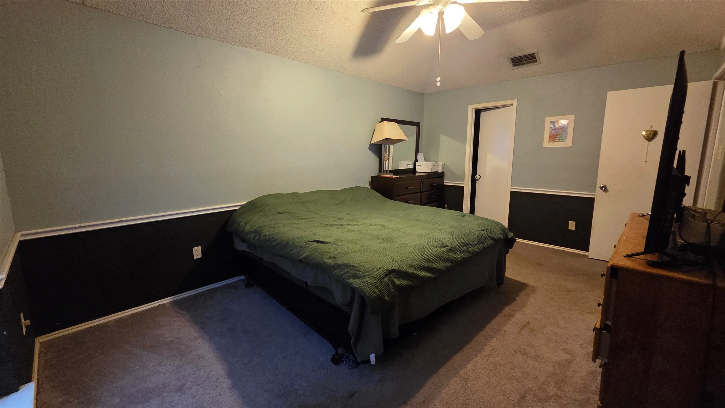 Carpeted flooring, ceiling fan with integrated lighting, wall trim, and a white interior door