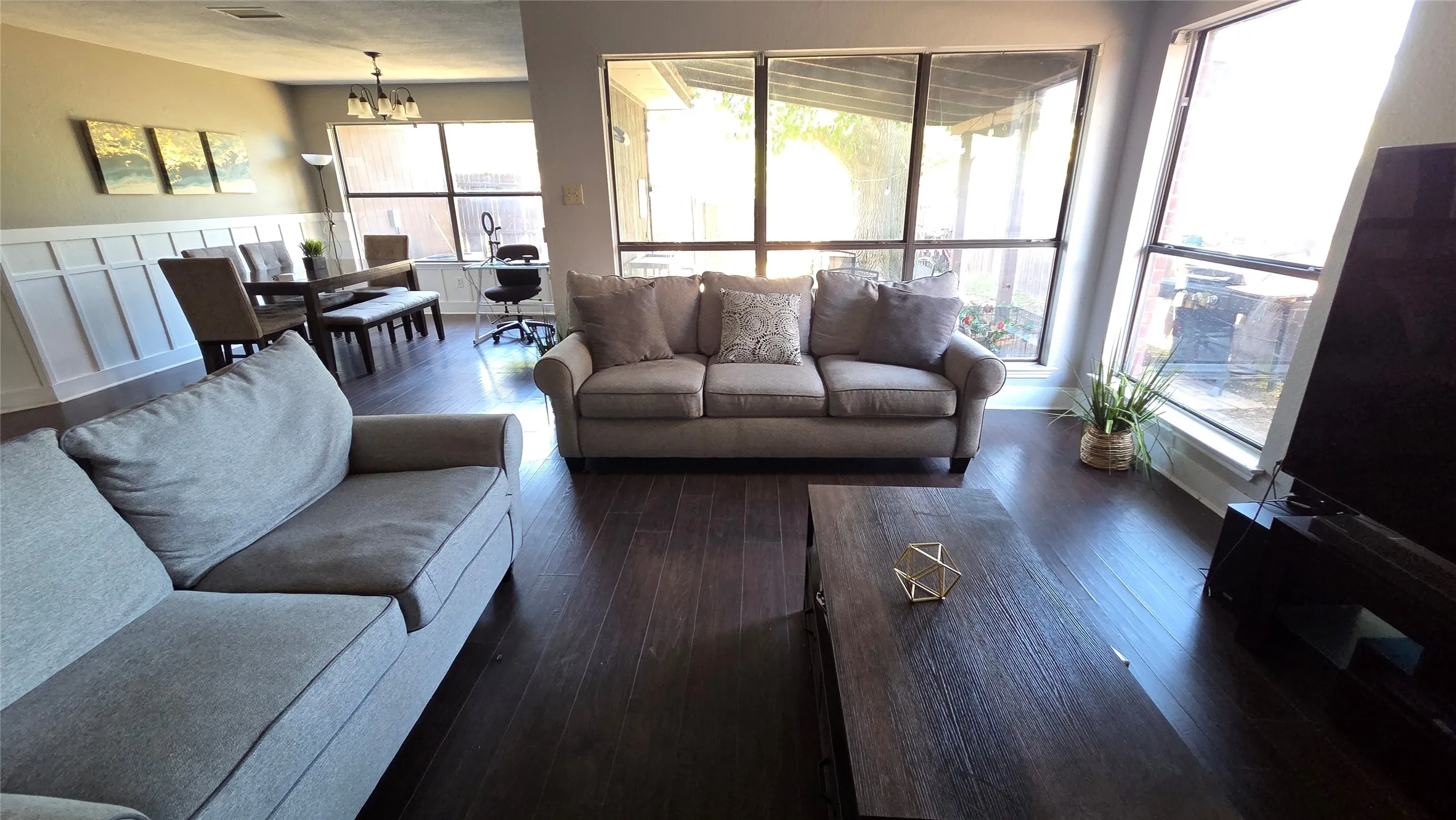 Wood-finish flooring, wainscoting paneling, multi-pane windows, and a chandelier lighting fixture
