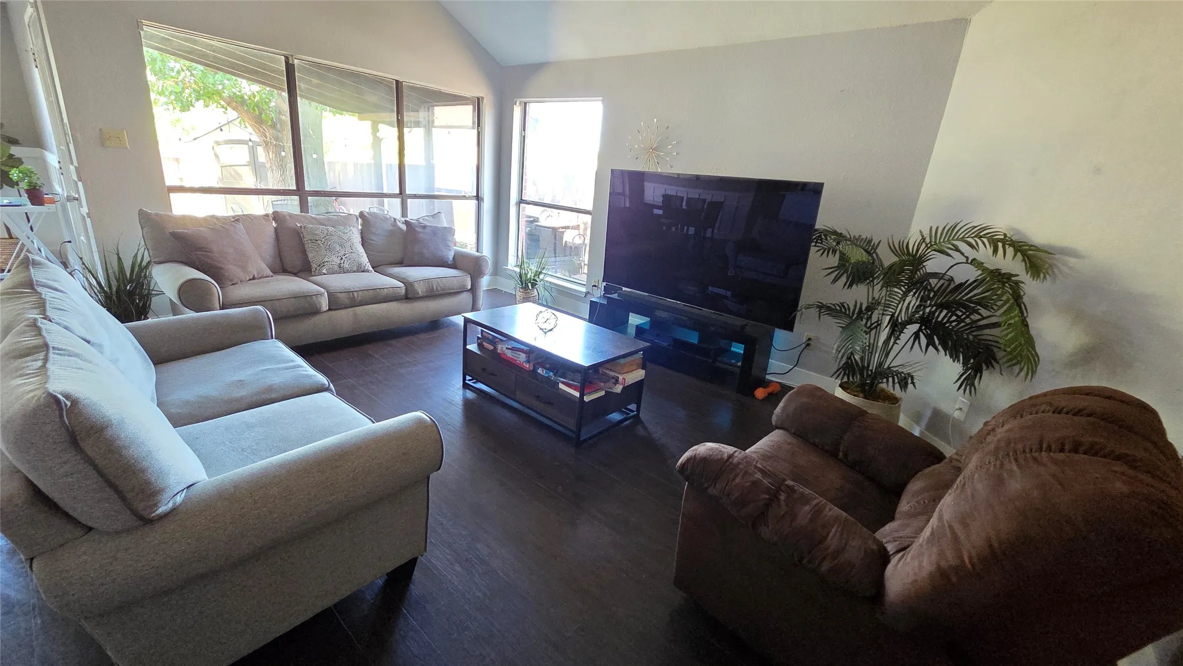 Dark wood-finish flooring with a multi-pane picture window and vaulted ceiling