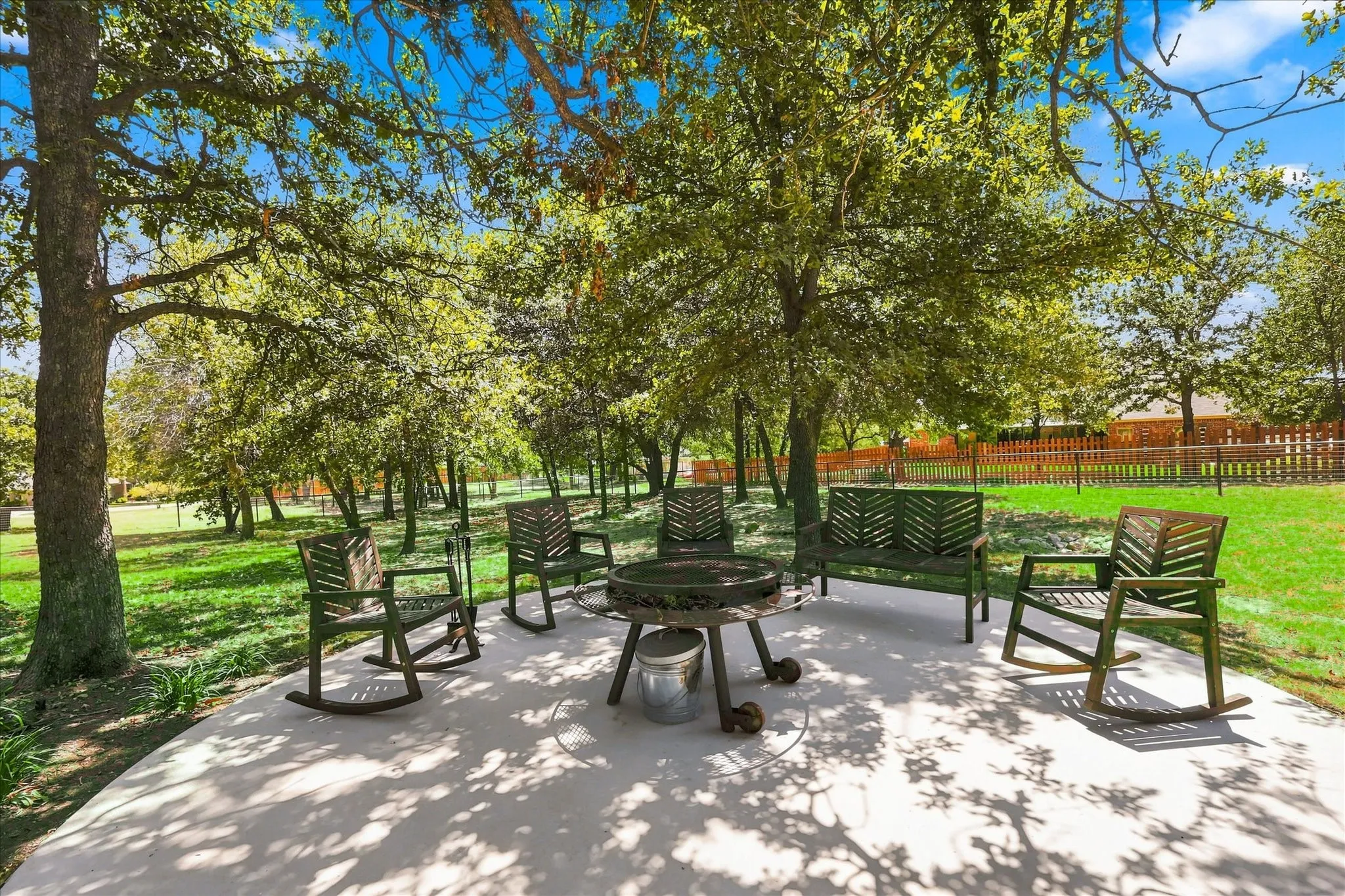 Expansive concrete patio area surrounded by mature trees