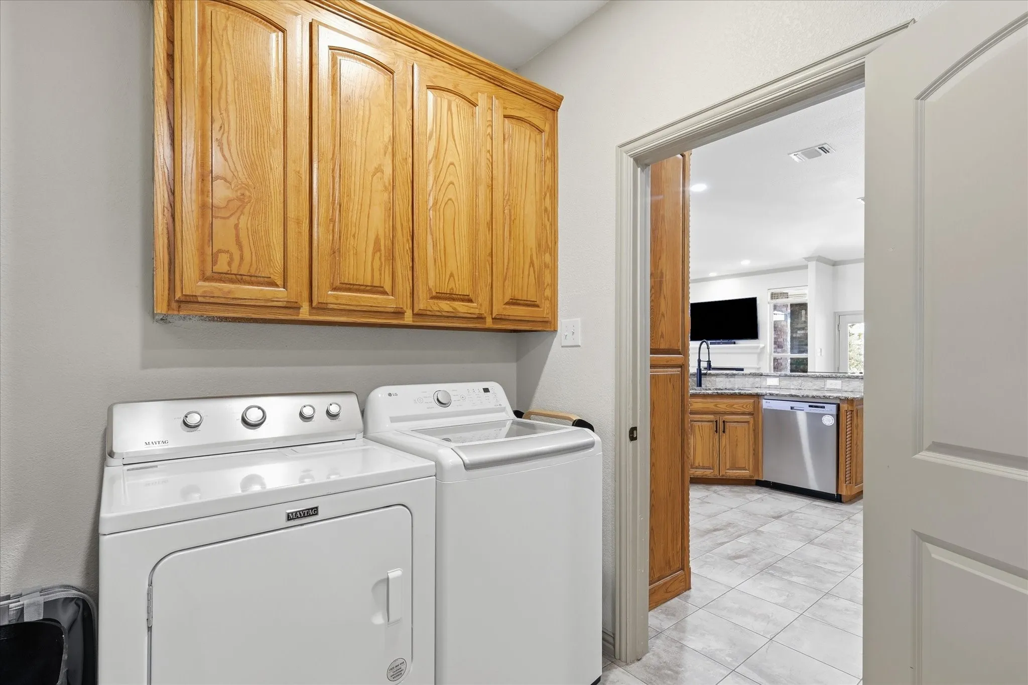 Laundry area featuring wood cabinetry, light gray wall paint, and tile flooring