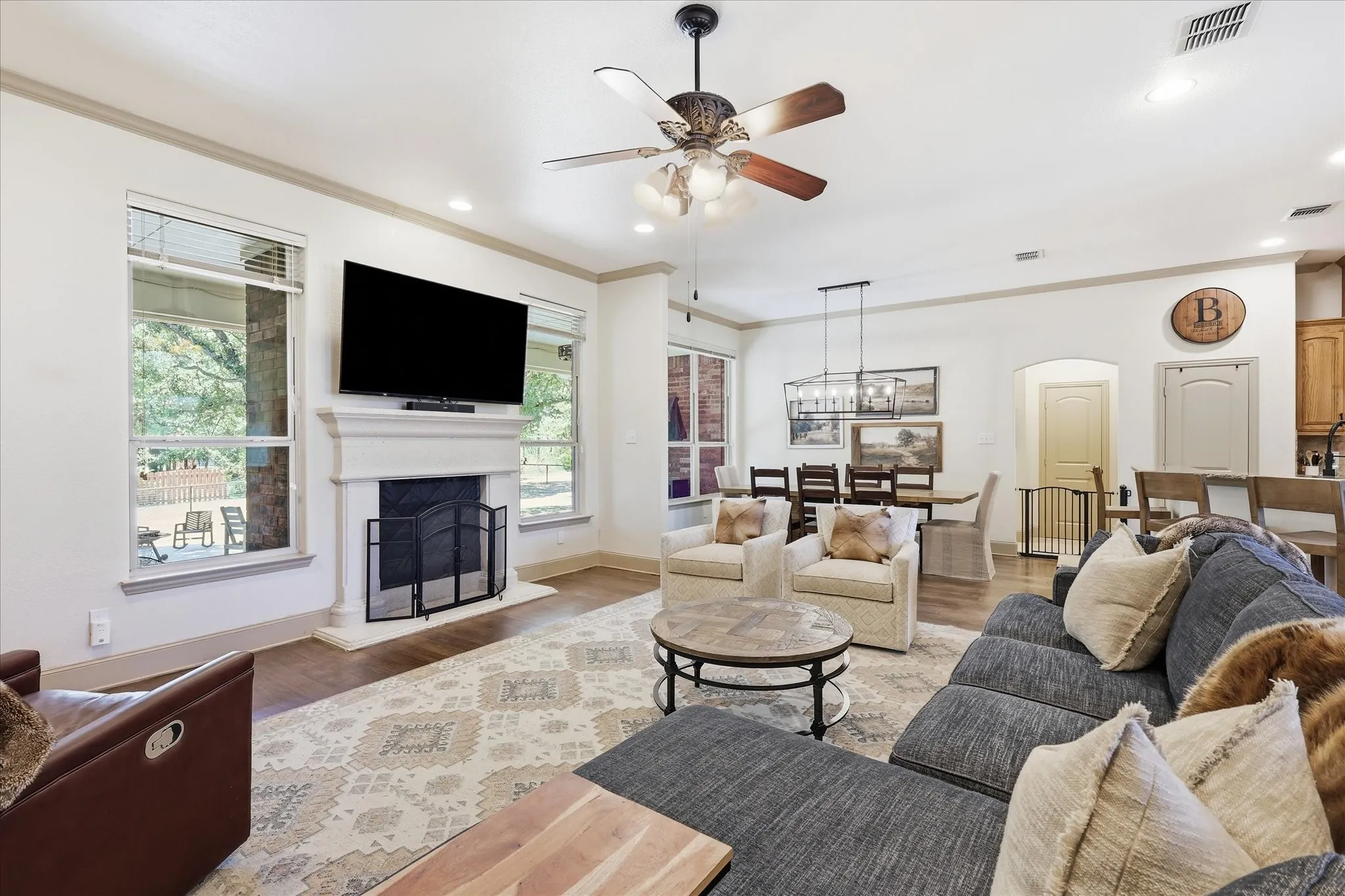 Living area with wood-finish flooring, a stone fireplace, and multiple windows