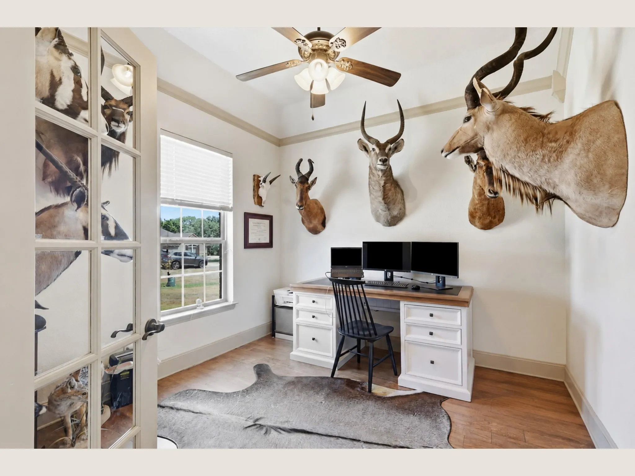 Wood-finish flooring with white baseboards, a ceiling fan with integrated lighting, a window with blinds, and French doors