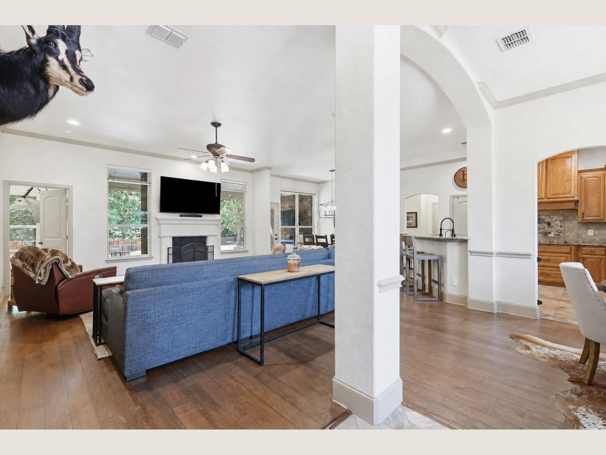 Open-concept living space featuring wood-finish flooring, a fireplace with a mantel, recessed lighting, and a ceiling fan