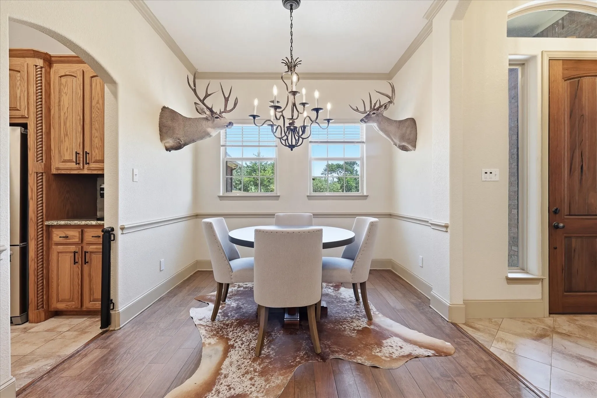 Wood-finish flooring, accent wall molding, and a built-in chandelier