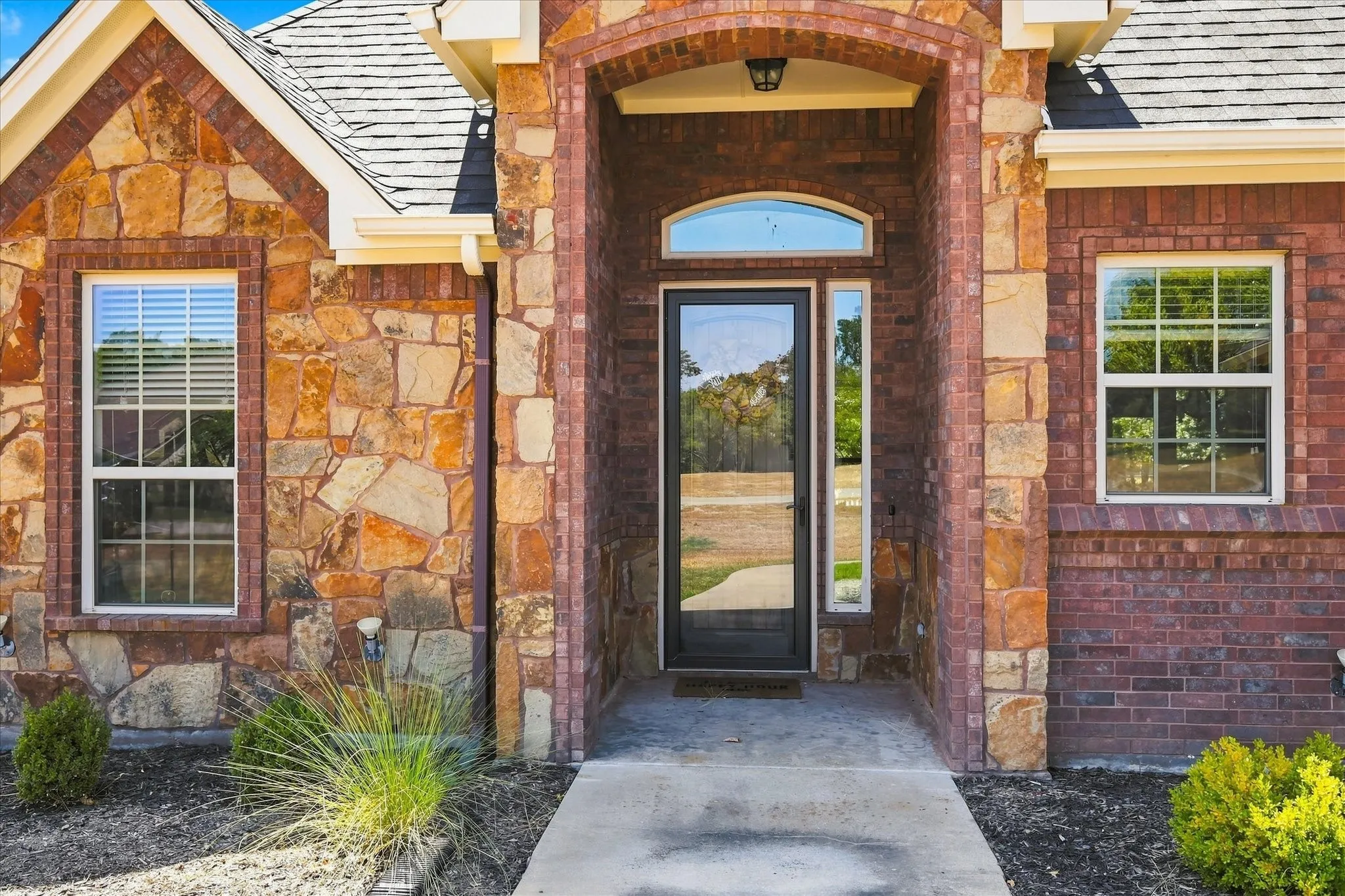 Stone and brick exterior with a prominent arched entry, transom window, and a full-light entry door