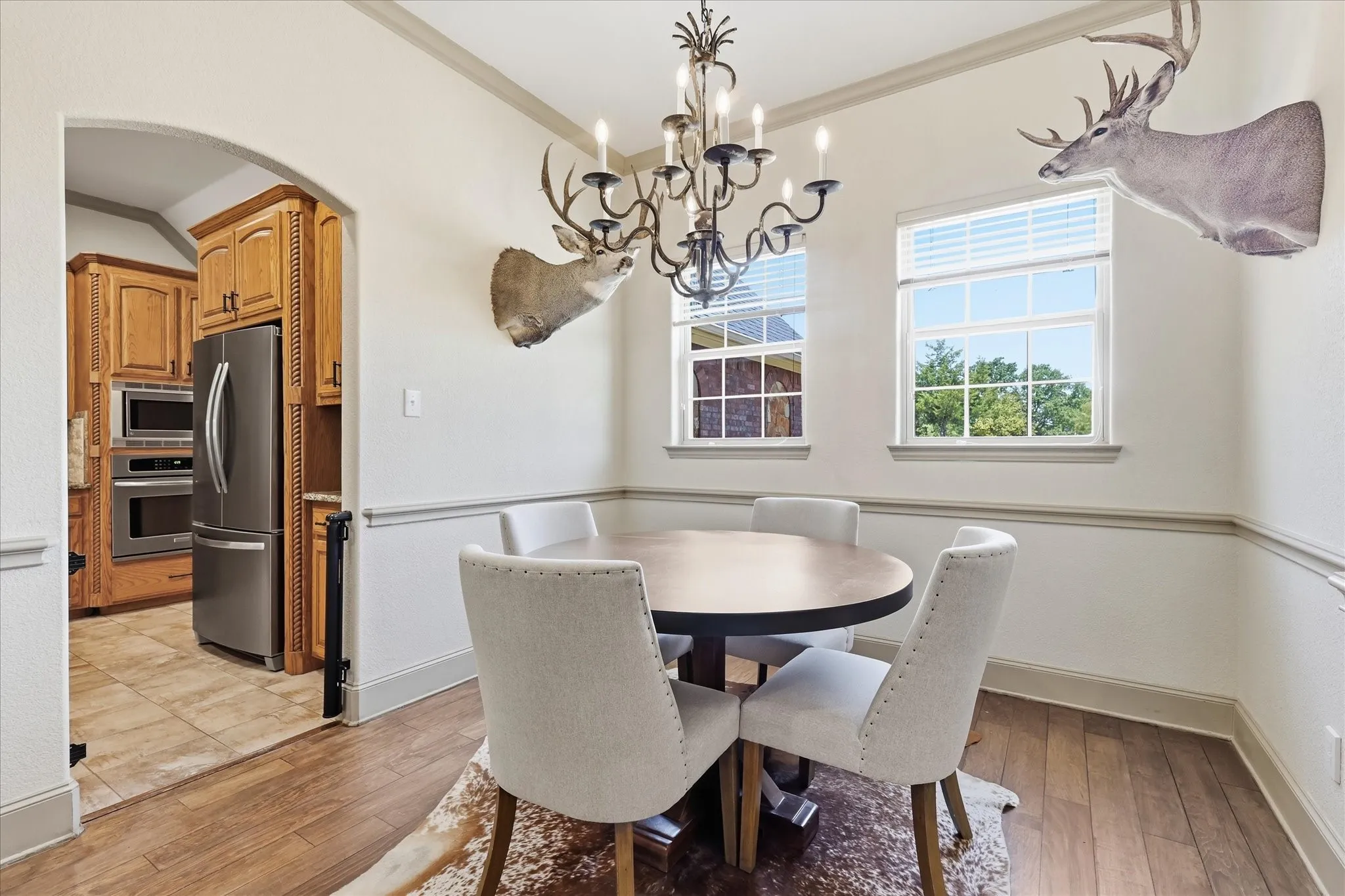 Wood-finish flooring, decorative chair rail, archway entry, recessed lighting, and a candelabra chandelier