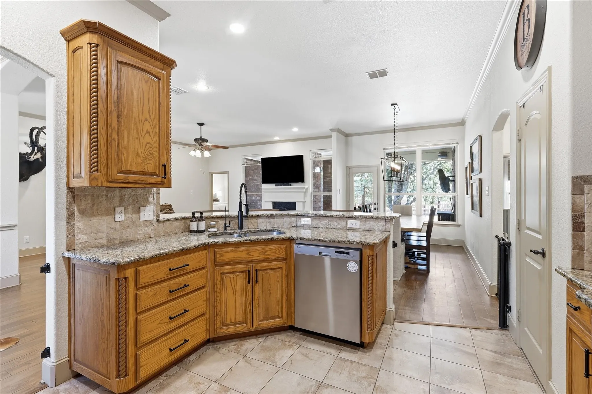 Kitchen with granite countertops, tile backsplash, wood cabinetry, and stainless steel dishwasher