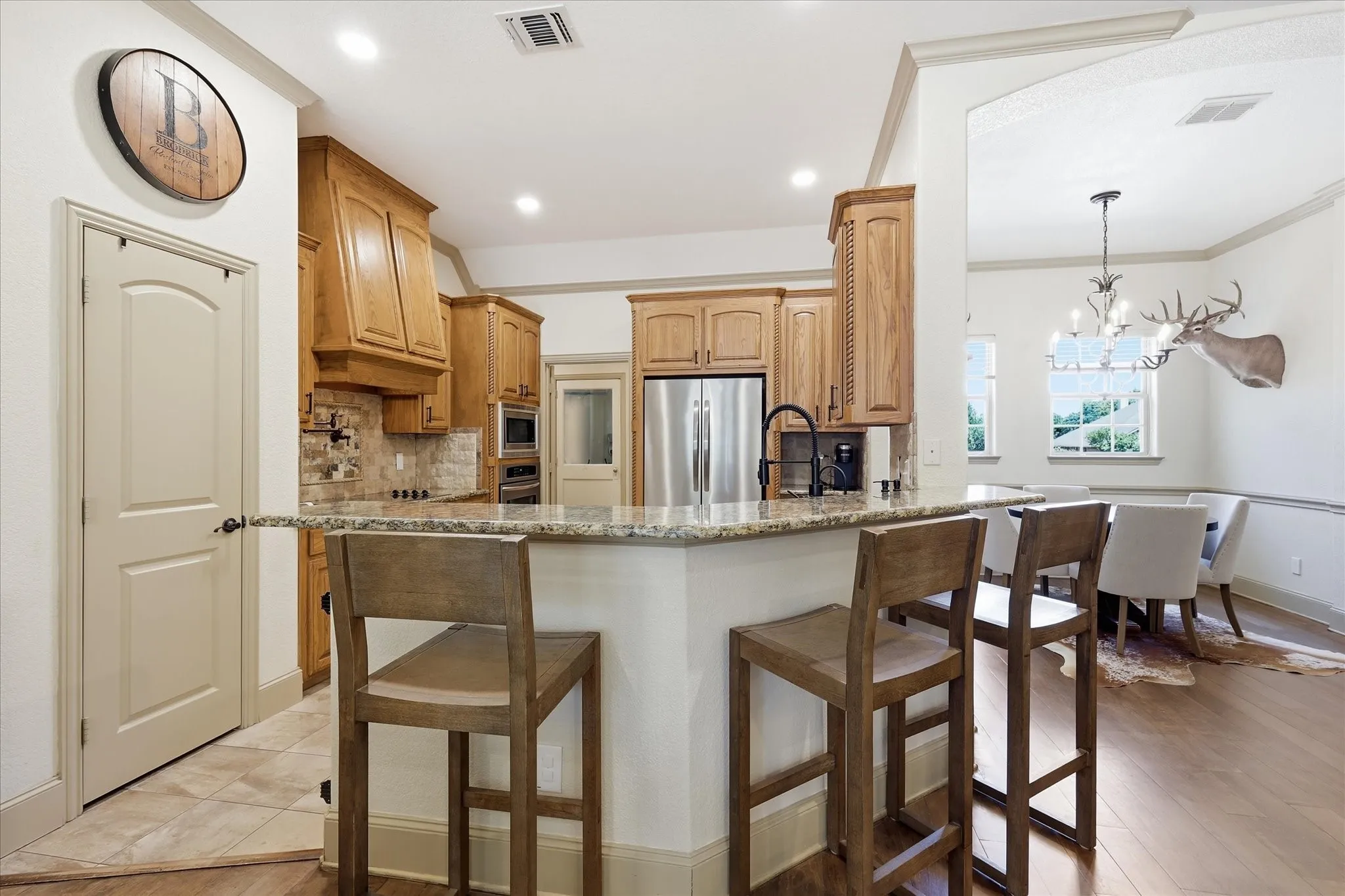 Kitchen featuring a breakfast bar with stone-finish countertop, stainless steel refrigerator, and recessed lighting