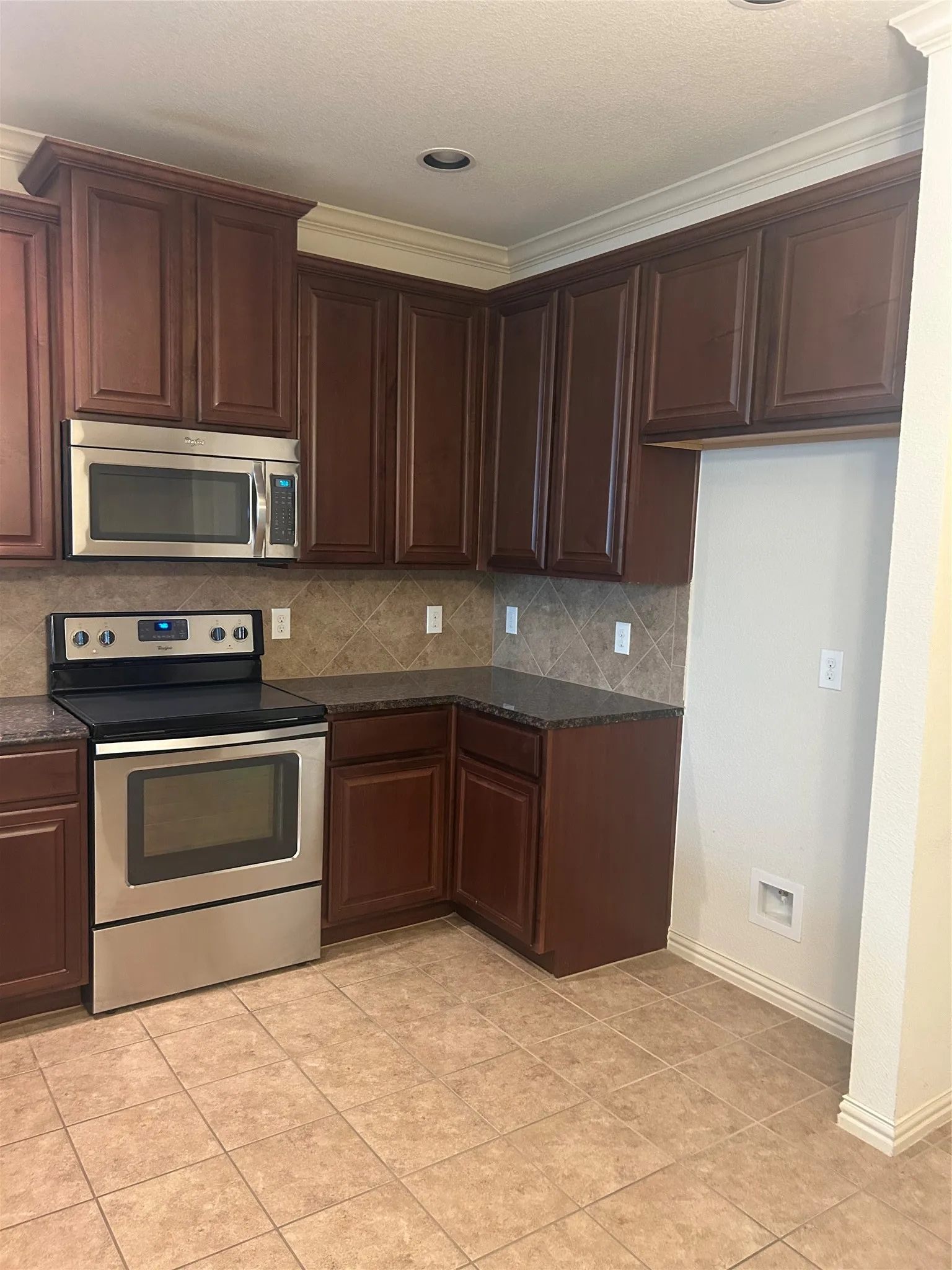 Kitchen featuring wood-finish cabinetry, stainless steel appliances and a tiled backsplash