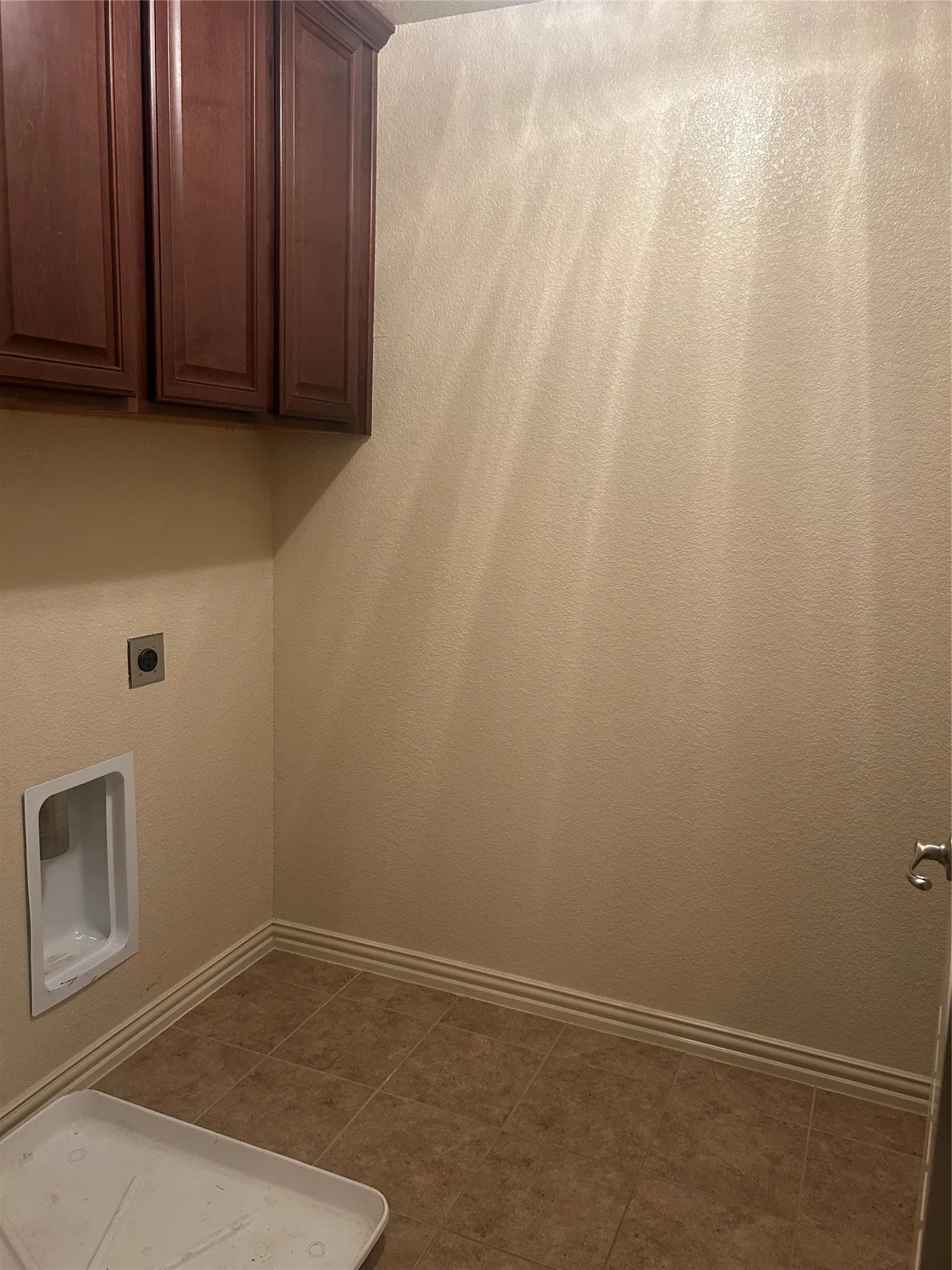 Integrated cabinetry with stained wood finish, tile flooring, and textured wall finish