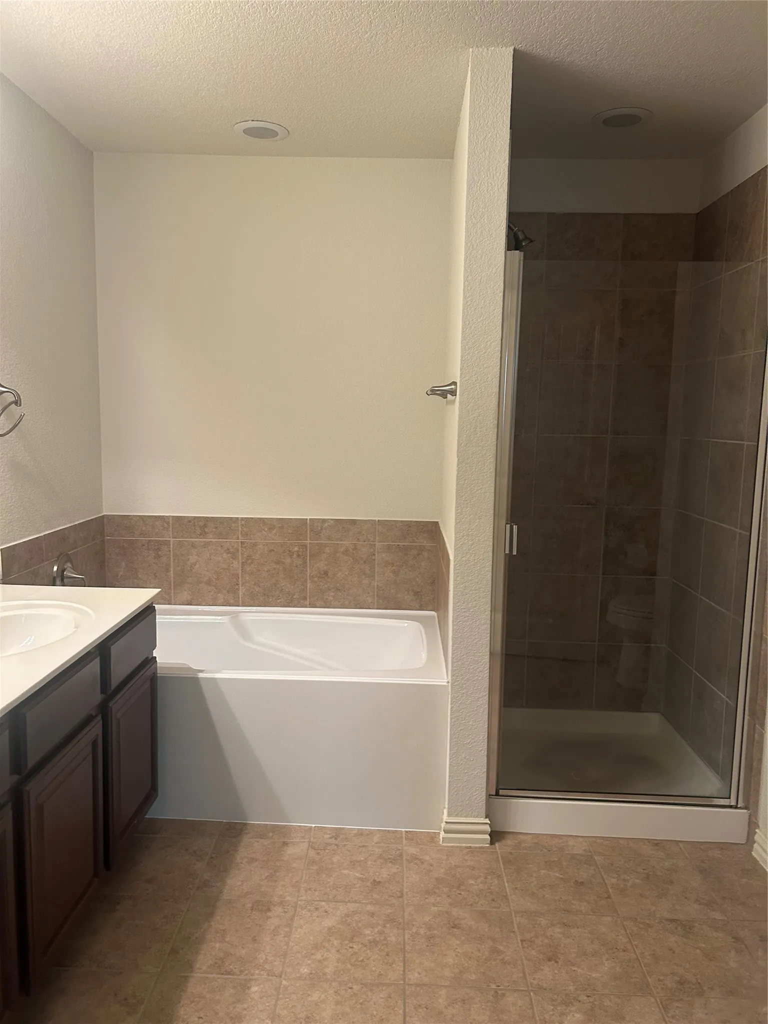 Recessed lighting, tile flooring, built-in bathtub, tile shower surround, and glass-enclosed shower
