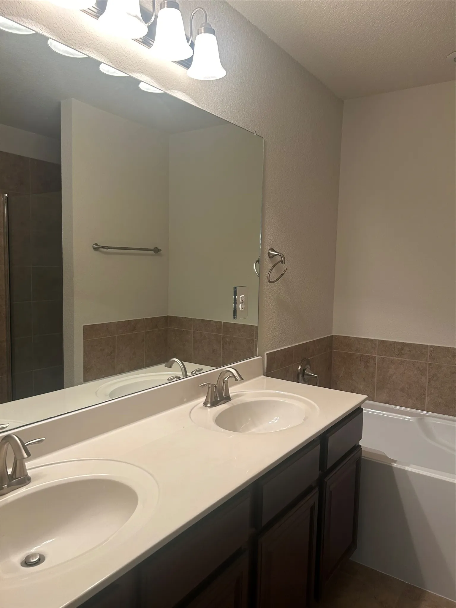 Dual-sink vanity with white ceramic basins and a quartz countertop, paired with dark wood cabinetry and brushed nickel faucets