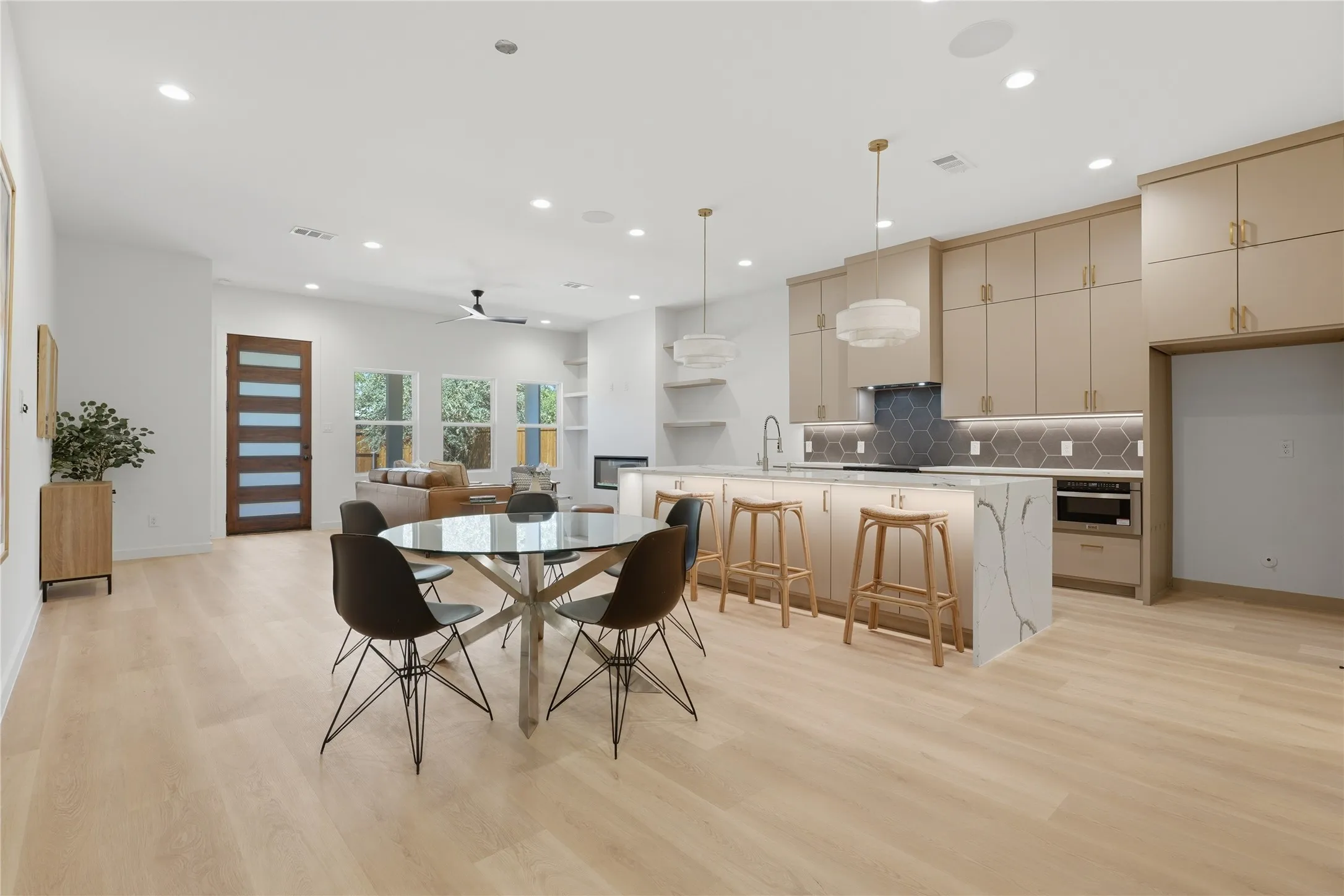 Open-concept living area with light wood-finish flooring, recessed lighting, and a modern ceiling fan